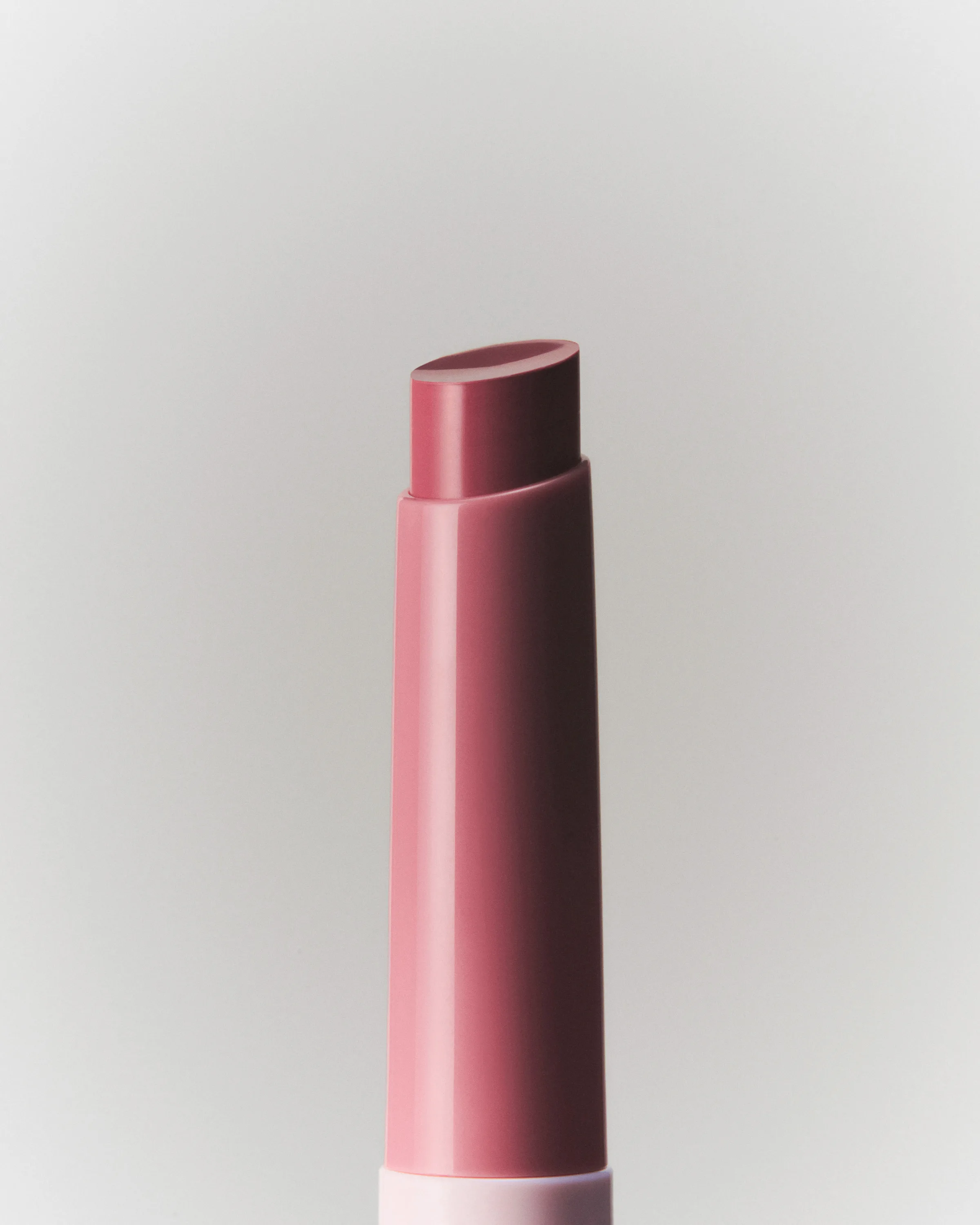 Still life close-up of a mauve pink lip stick with angled tip against a soft grey background, for Kylie Cosmetics.