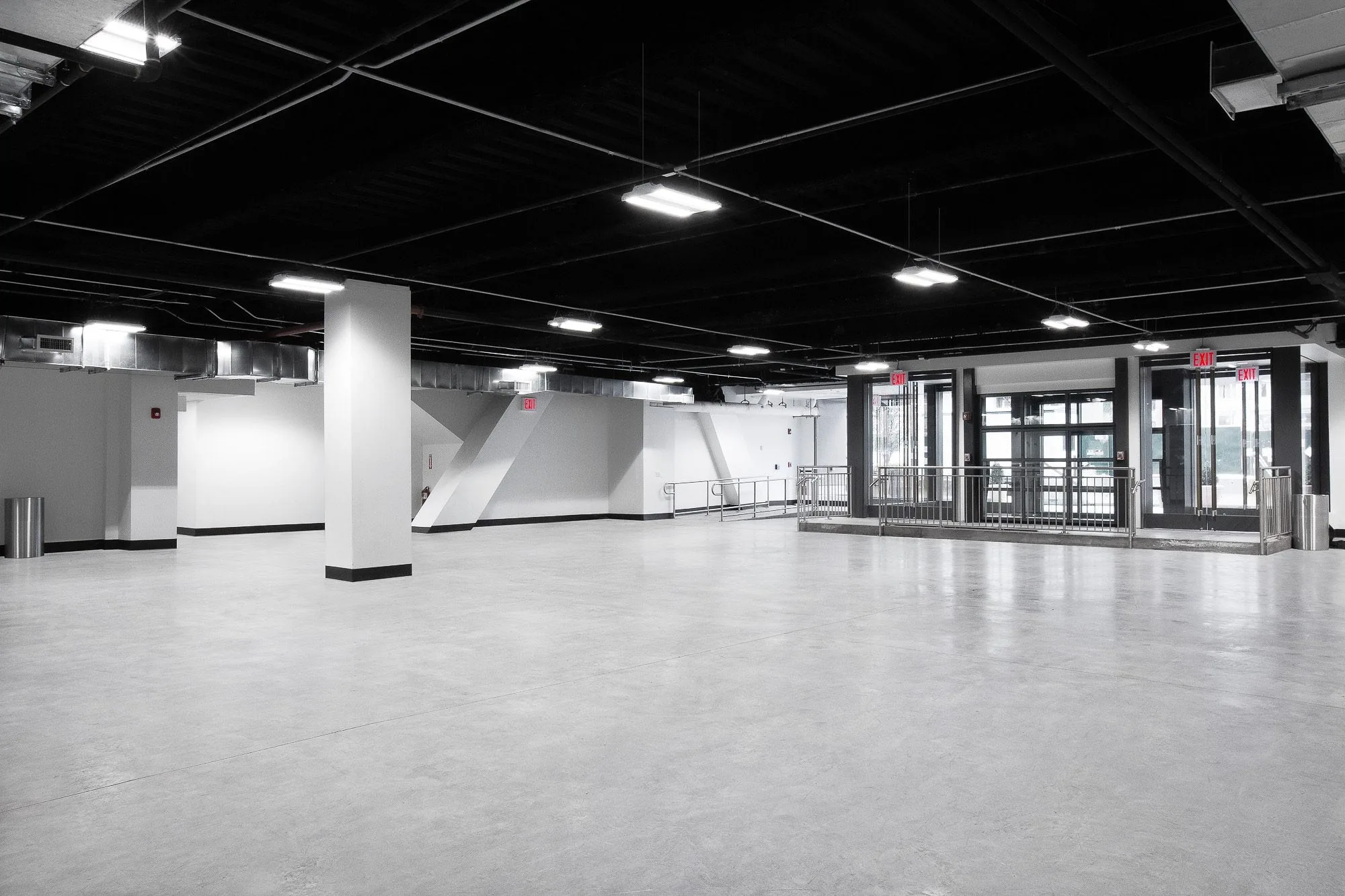 Empty Studio 2 at Slate Studios with grey concrete floor, white columns, black ceiling and glass entrance doors.