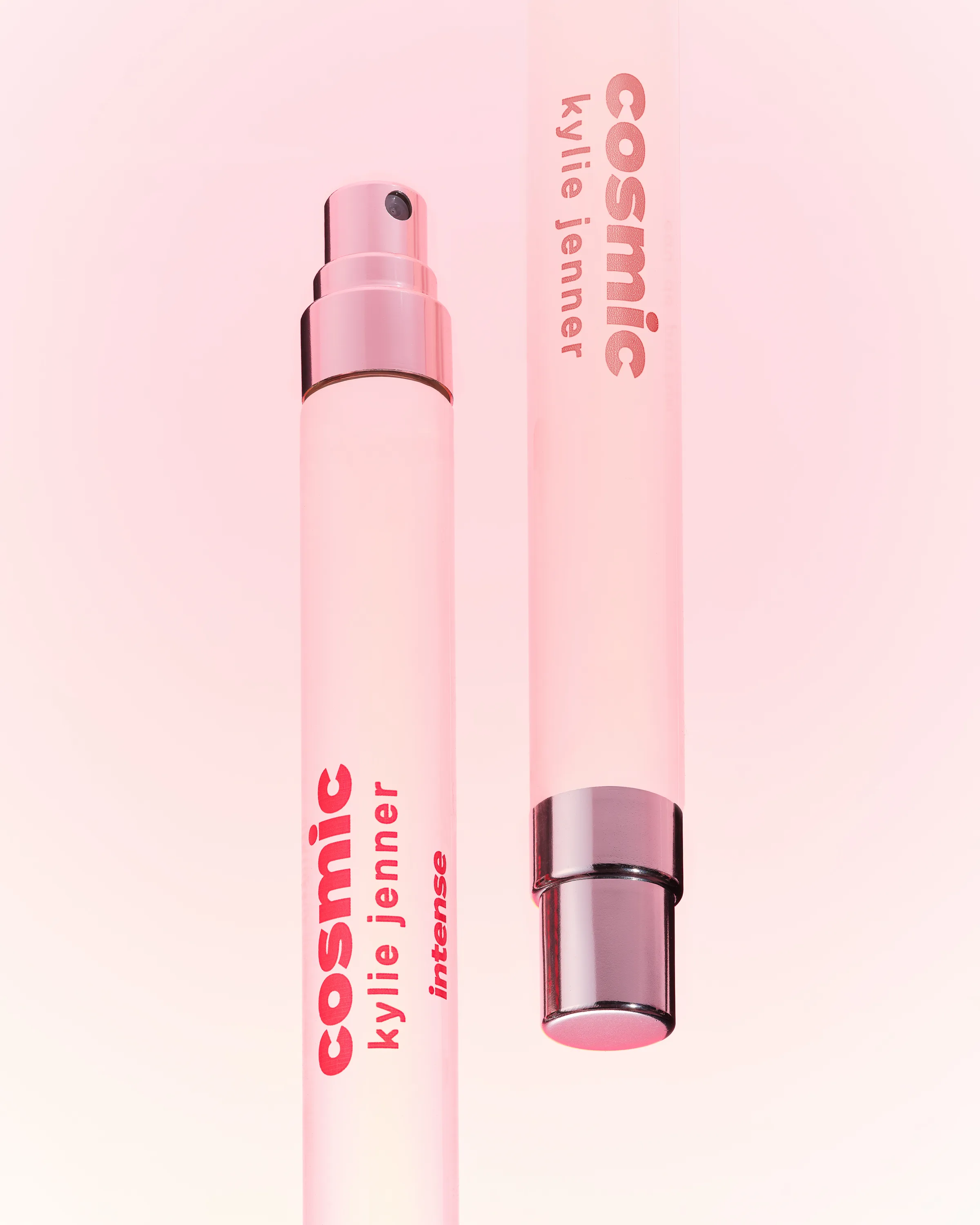 Two pink Cosmic Kylie Jenner 10ml pen sprays with chrome caps, one inverted, on a soft pink background, for Kylie Cosmetics.