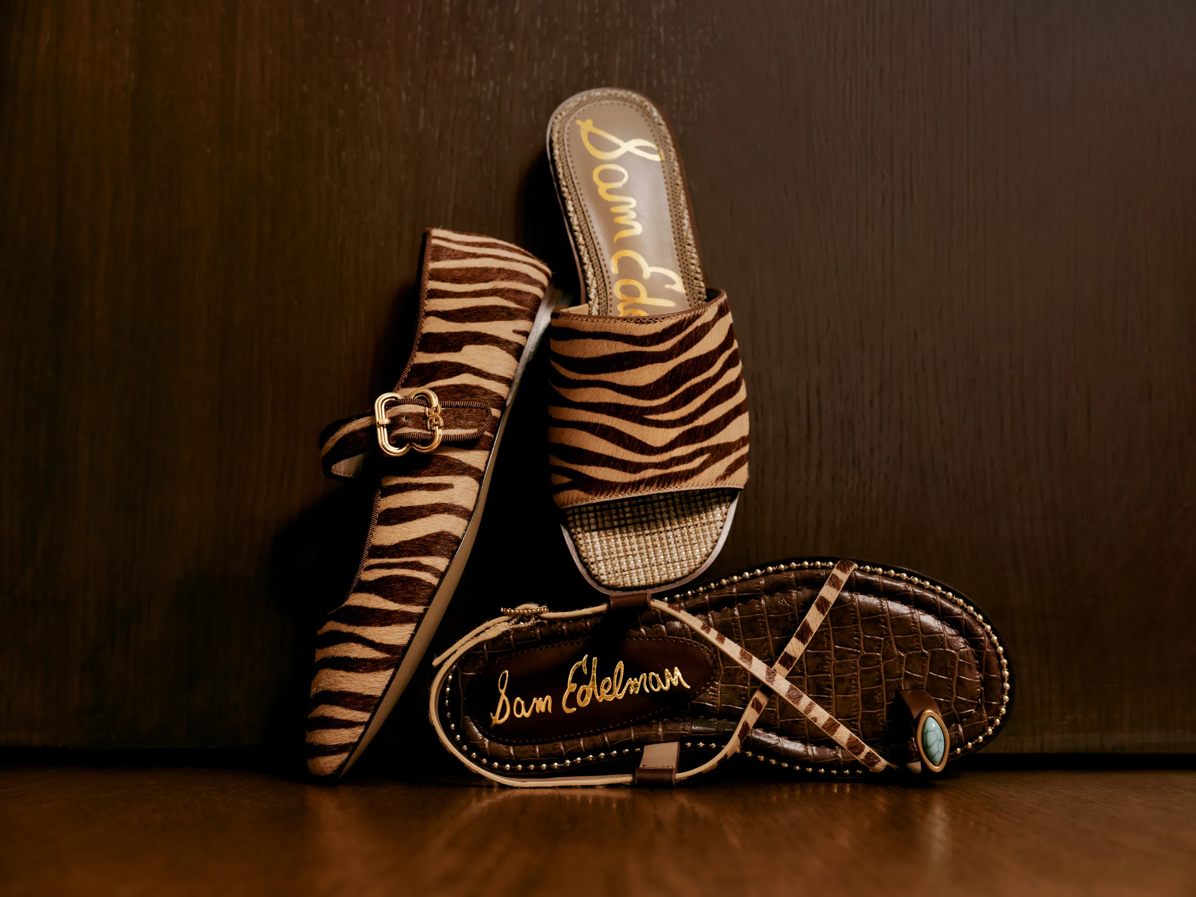 Zebra-print calf hair Mary Jane flat, slide and strappy croc-embossed sandal against dark wood, for Sam Edelman.
