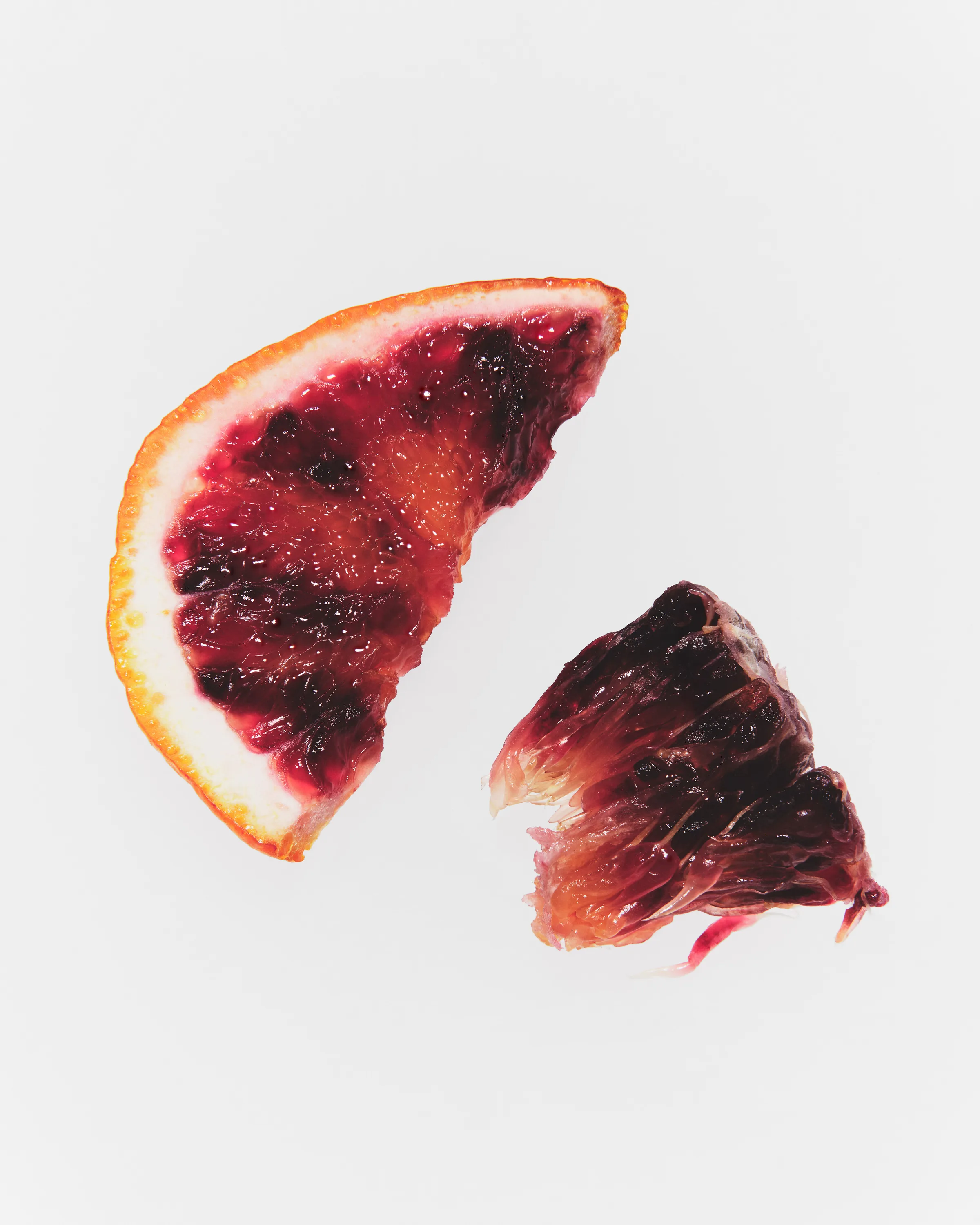 Still life of a blood orange wedge and torn segment on a white background, an ingredient shot, for Kylie Cosmetics.
