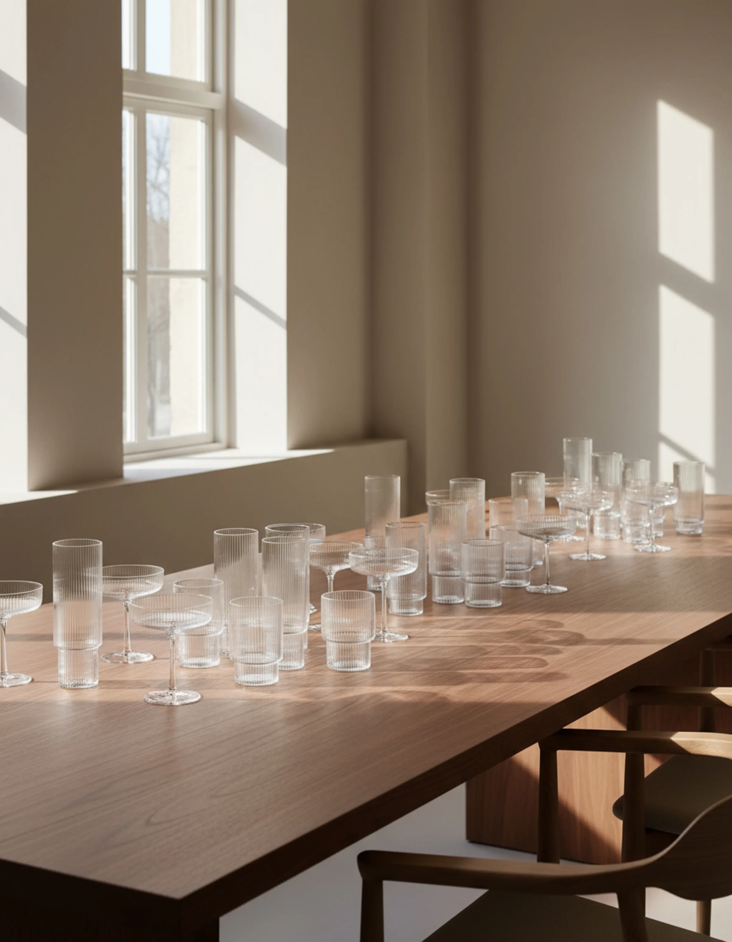 CGI render of ribbed glasses and coupes lined up on a long walnut table in a sunlit room. Ferm Living AI Concept.