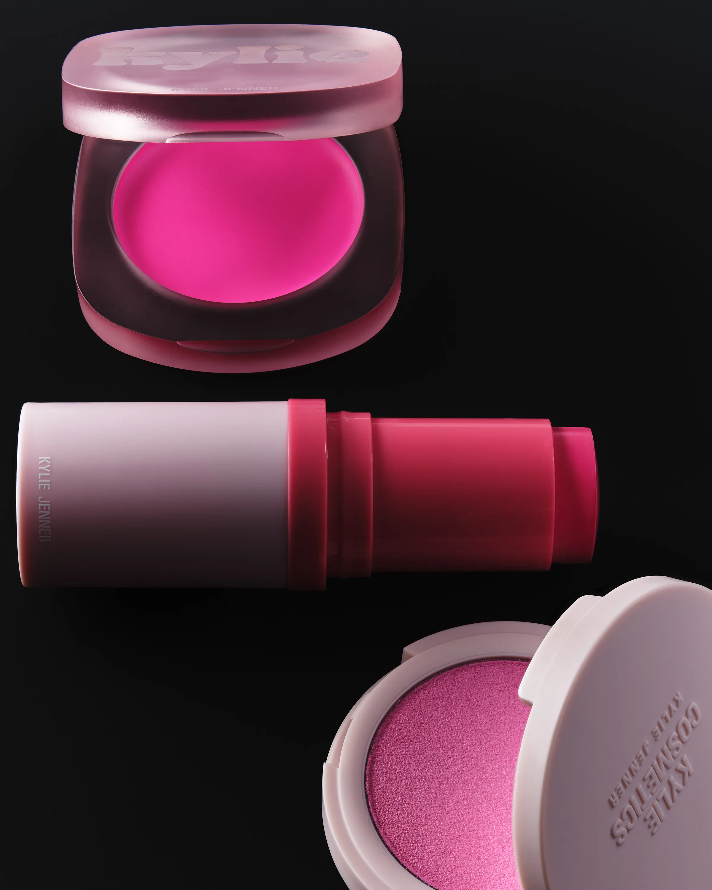 Pink cream blush compact, balm stick and powder blush open on a black background, for Kylie Cosmetics.