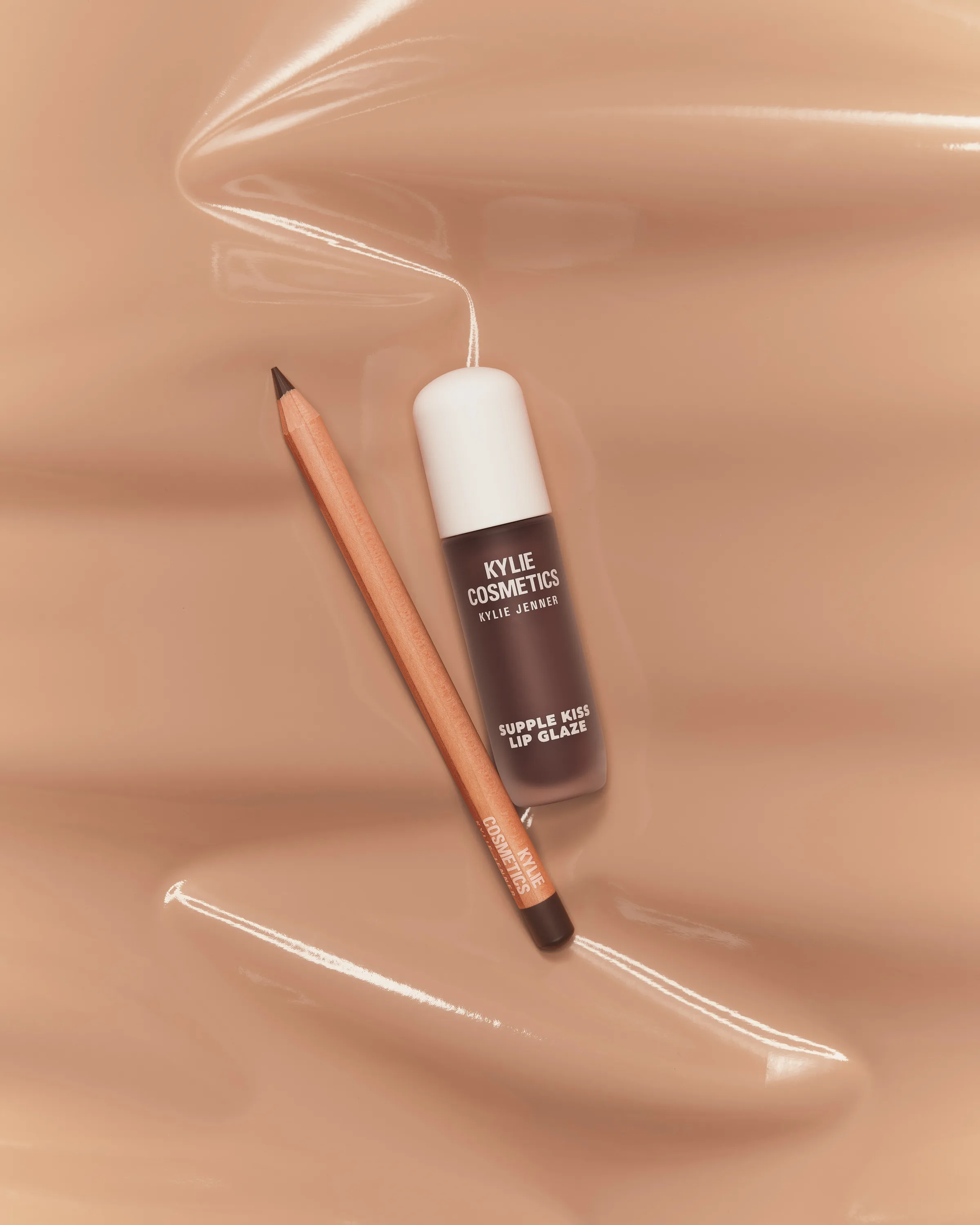 Espresso Supple Kiss Lip Glaze and lip liner pencil laid on swirled nude glossy texture, for Kylie Cosmetics.