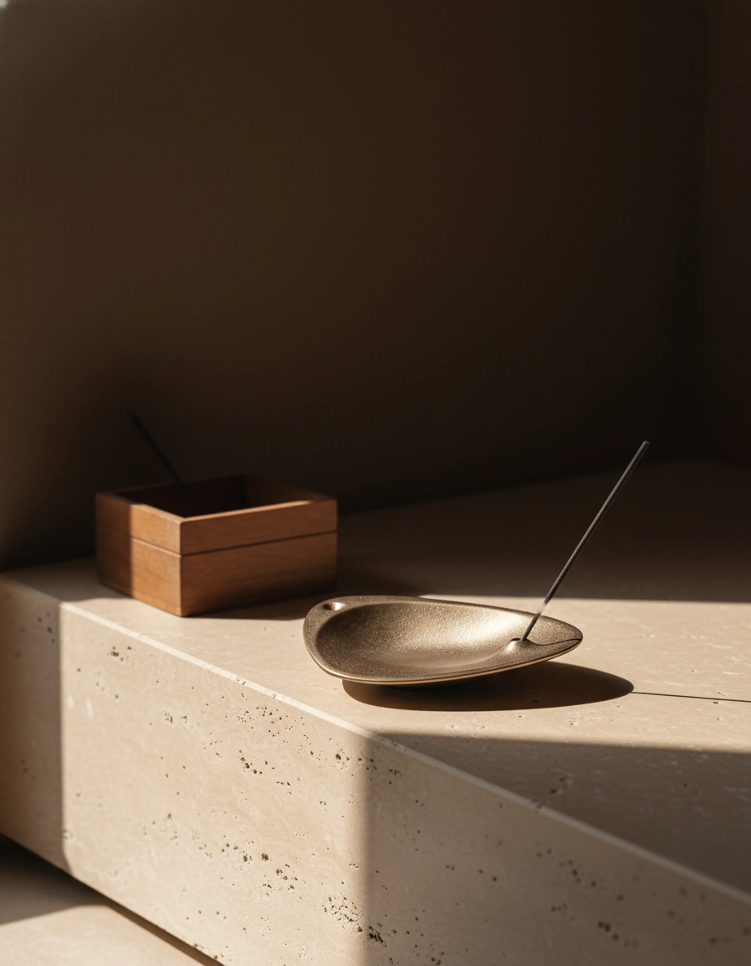 AI image of a bronze incense holder and wooden box on a travertine ledge in warm, angled sunlight. Aesop AI Concept.