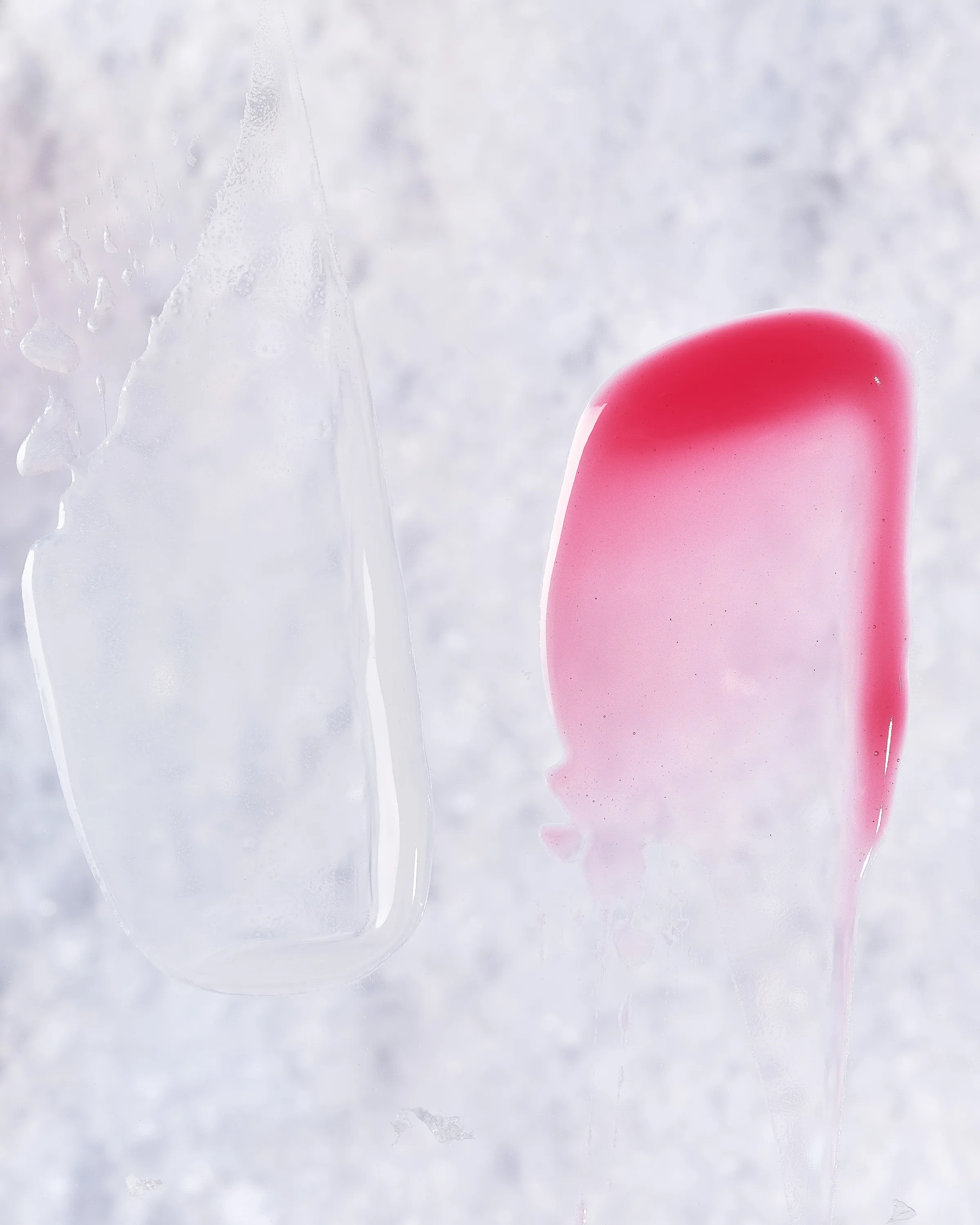Clear and pink lip gloss swatches smeared across a frosty white icy surface, for Kylie Cosmetics.