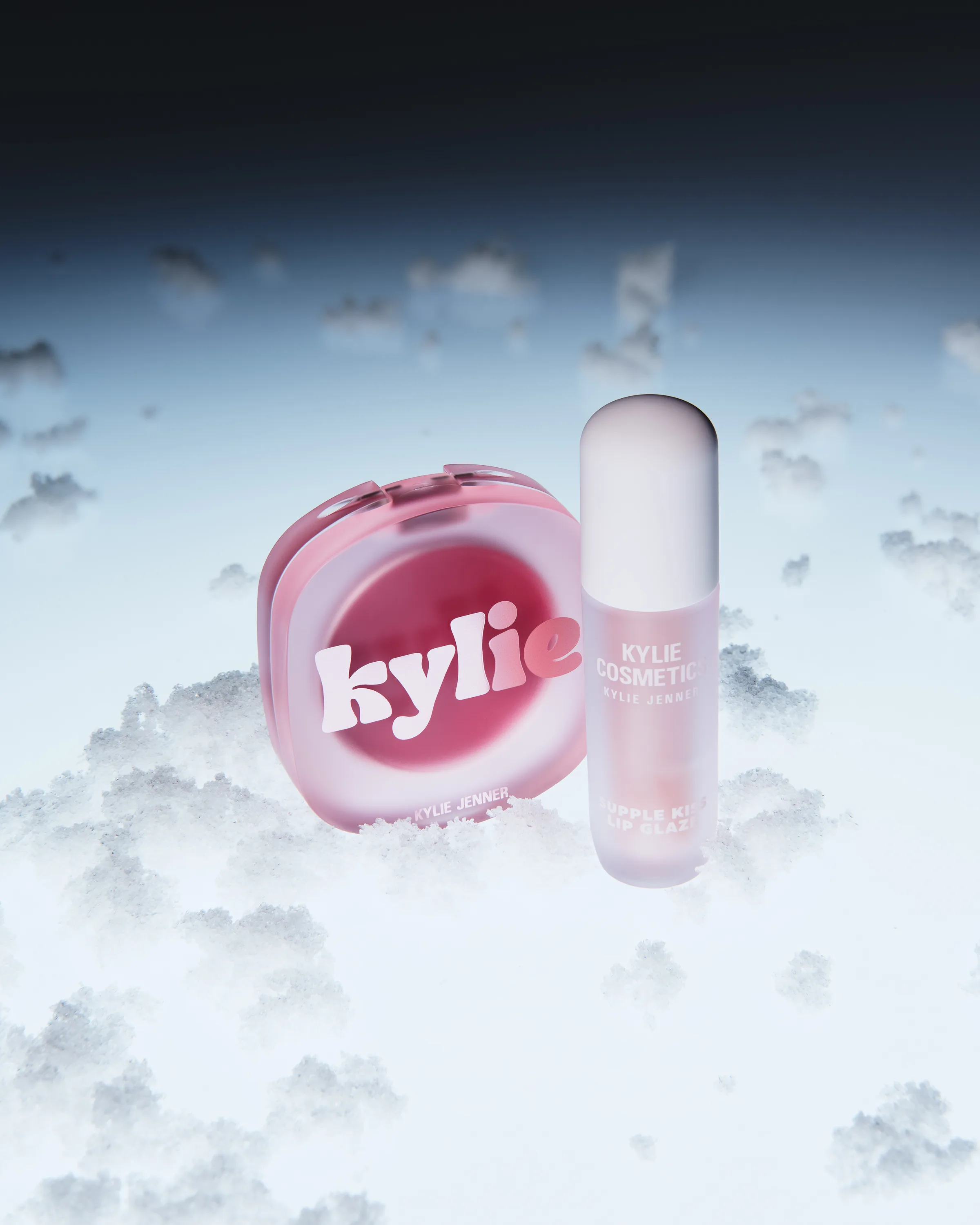 Pink blush compact and Supple Kiss lip glaze resting on frosty snow under a dark blue sky, for Kylie Cosmetics.