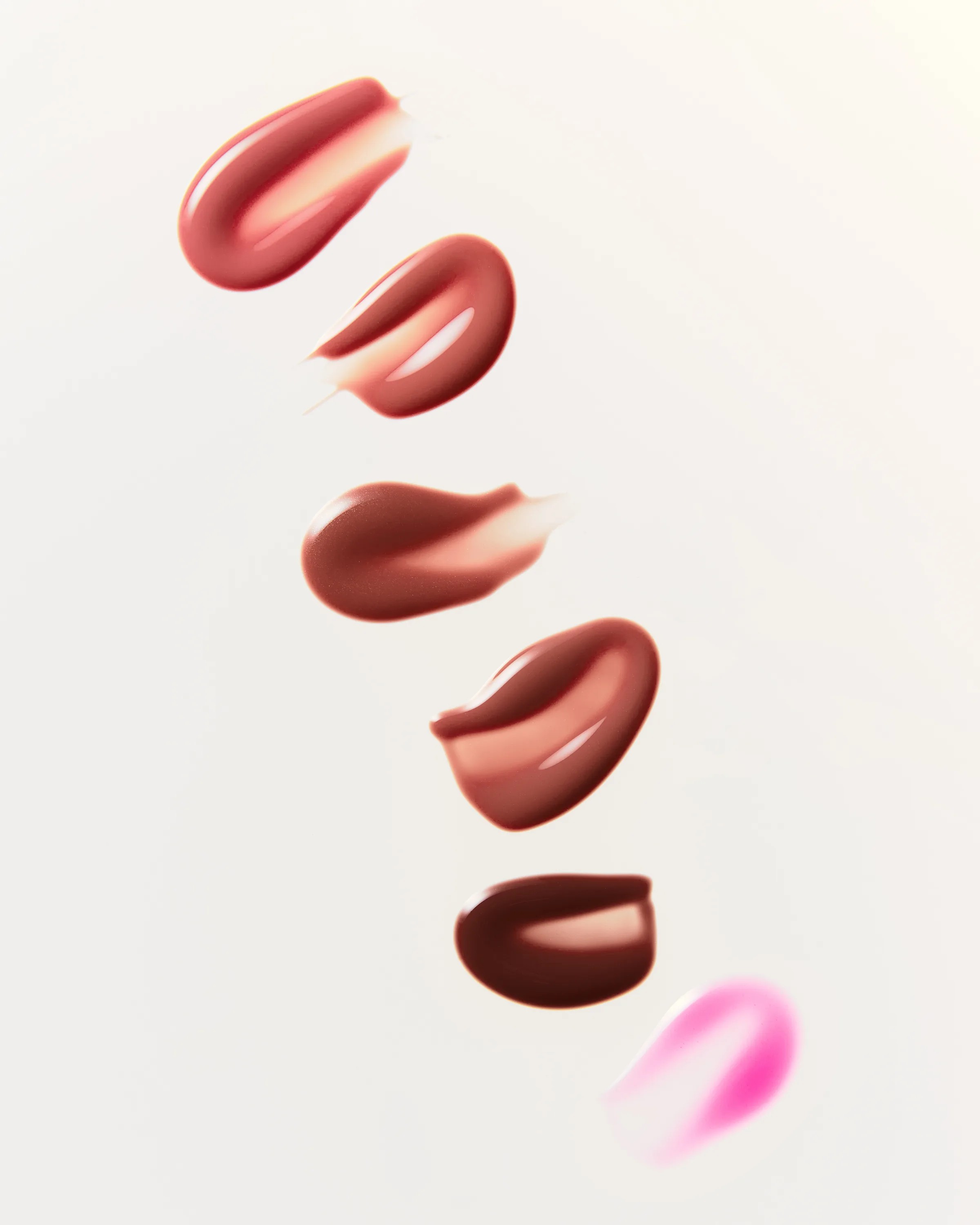 Glossy lip glaze swatches in pink, nude and brown shades arranged diagonally on a cream background, for Kylie Cosmetics.