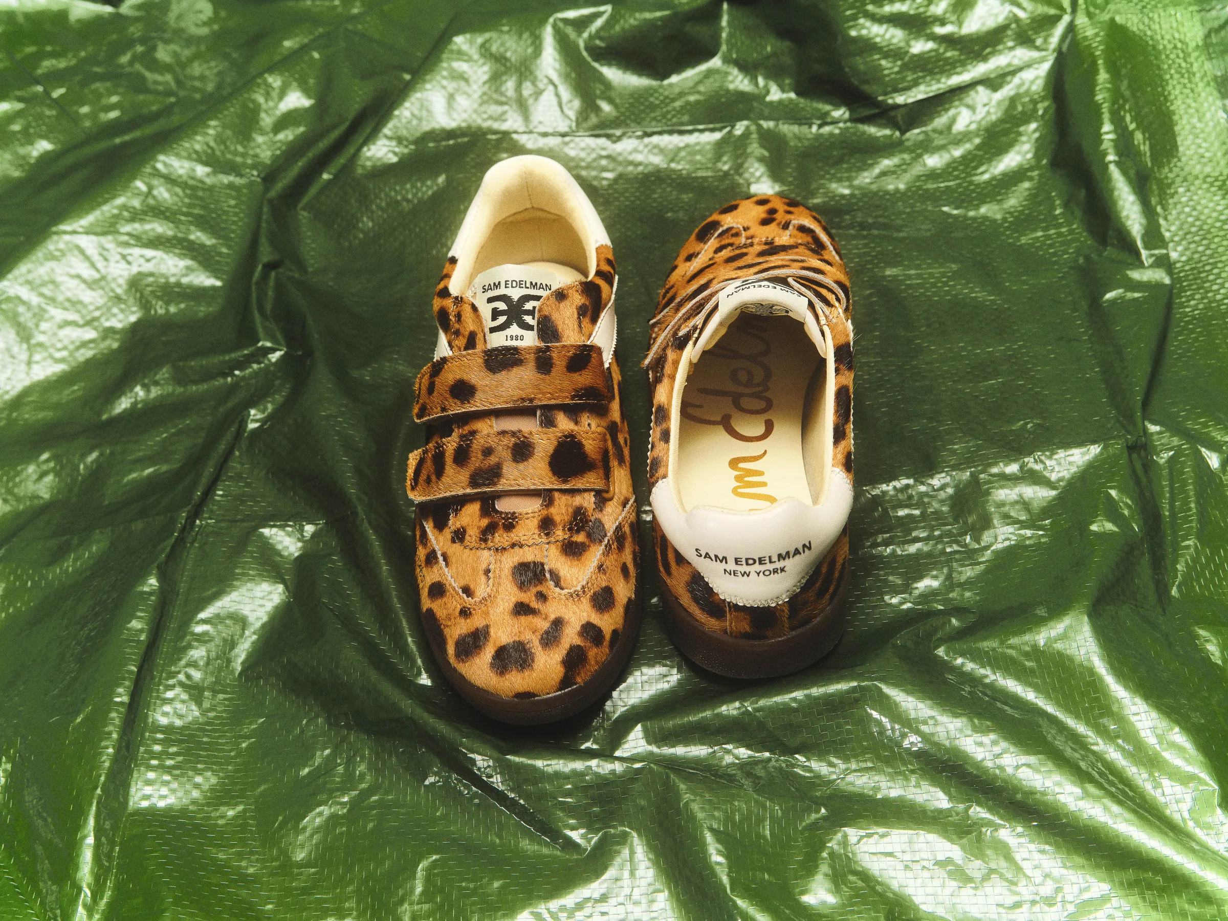 Leopard-print calf hair sneakers with hook-and-loop straps on crinkled green plastic sheeting, for Sam Edelman.