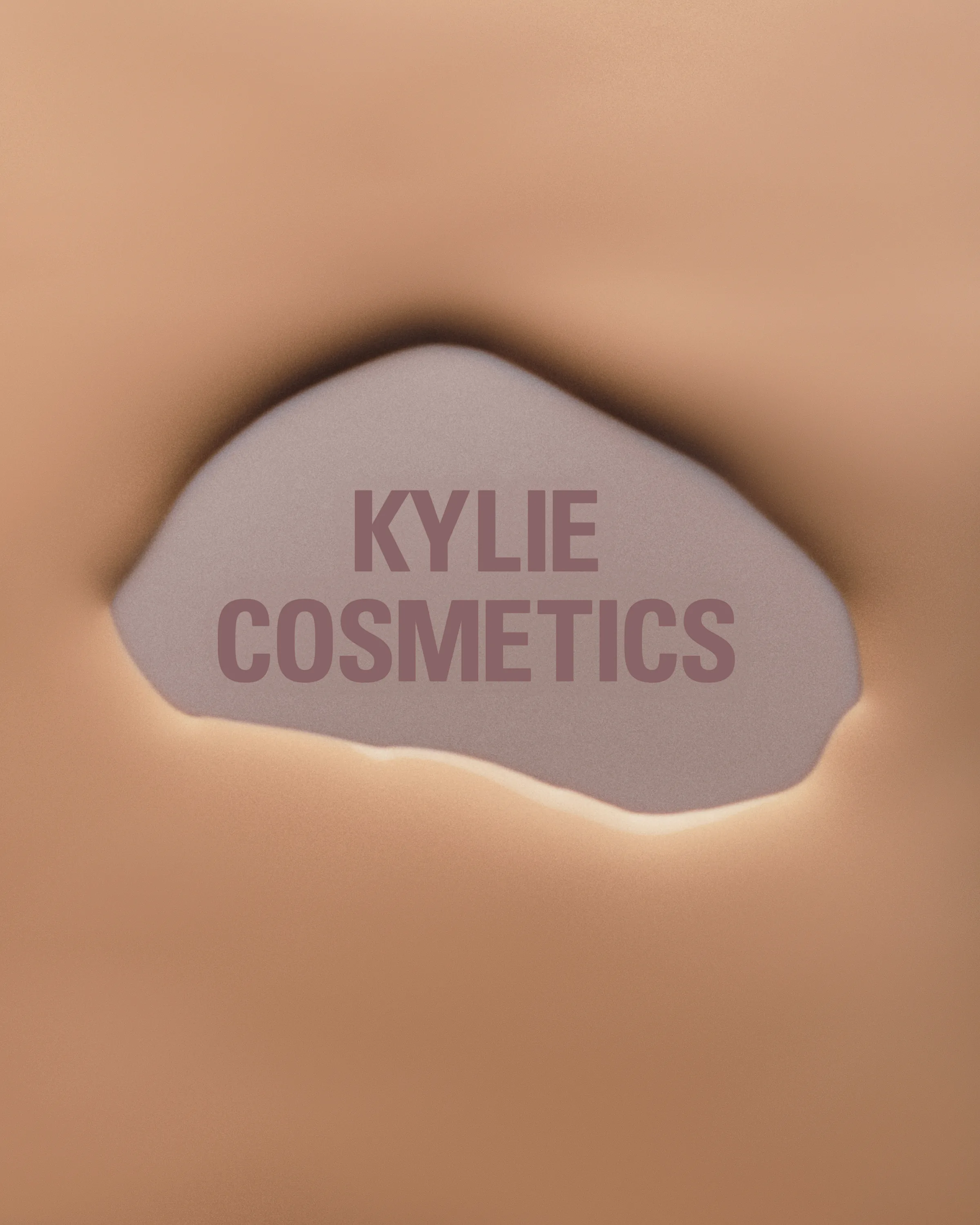 Skin-tone surface torn open to reveal a mauve Kylie Cosmetics wordmark beneath, for Kylie Cosmetics.