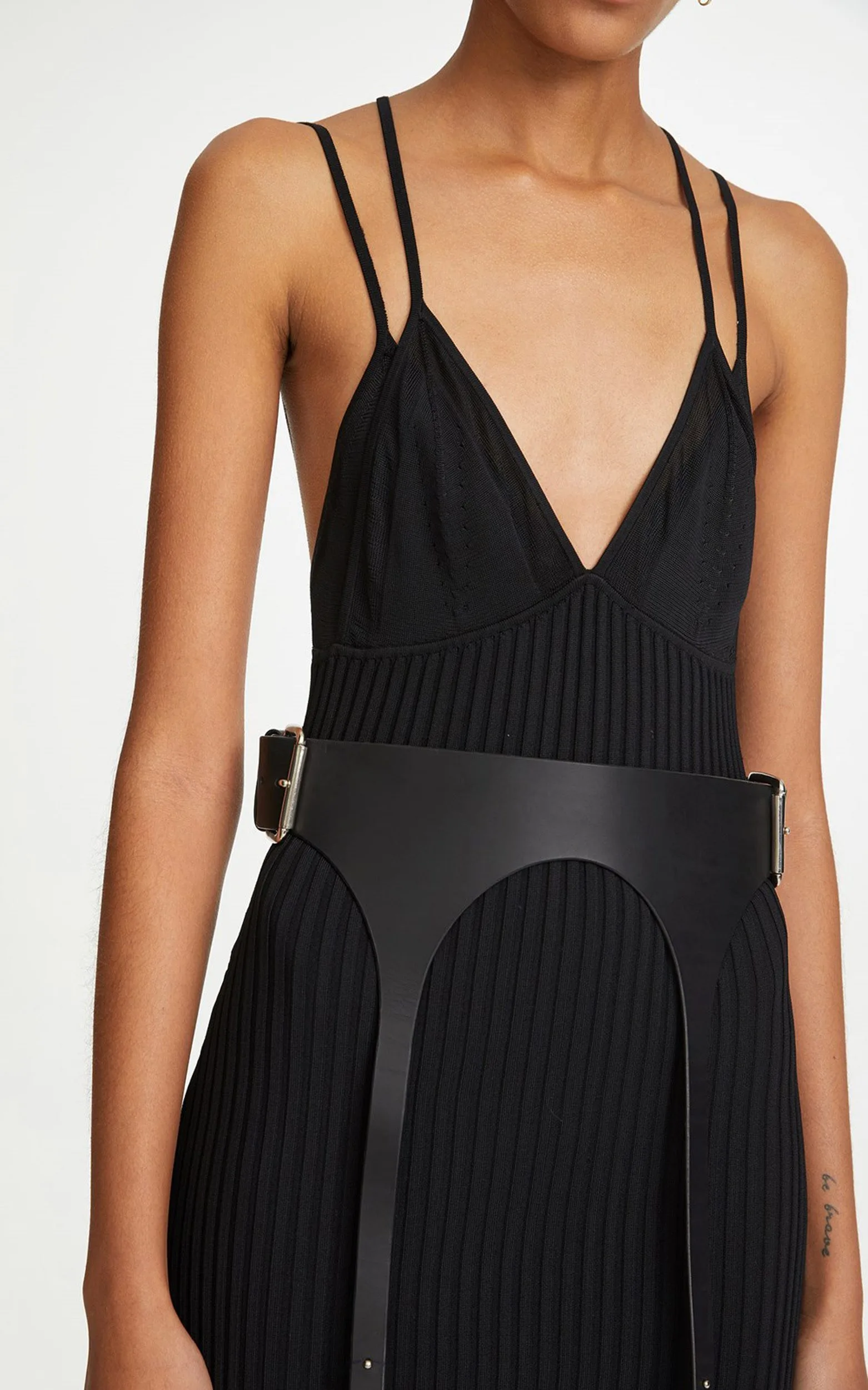 Model in a black ribbed knit strappy dress with a wide black leather garter-style belt on a white background, for Dion Lee.