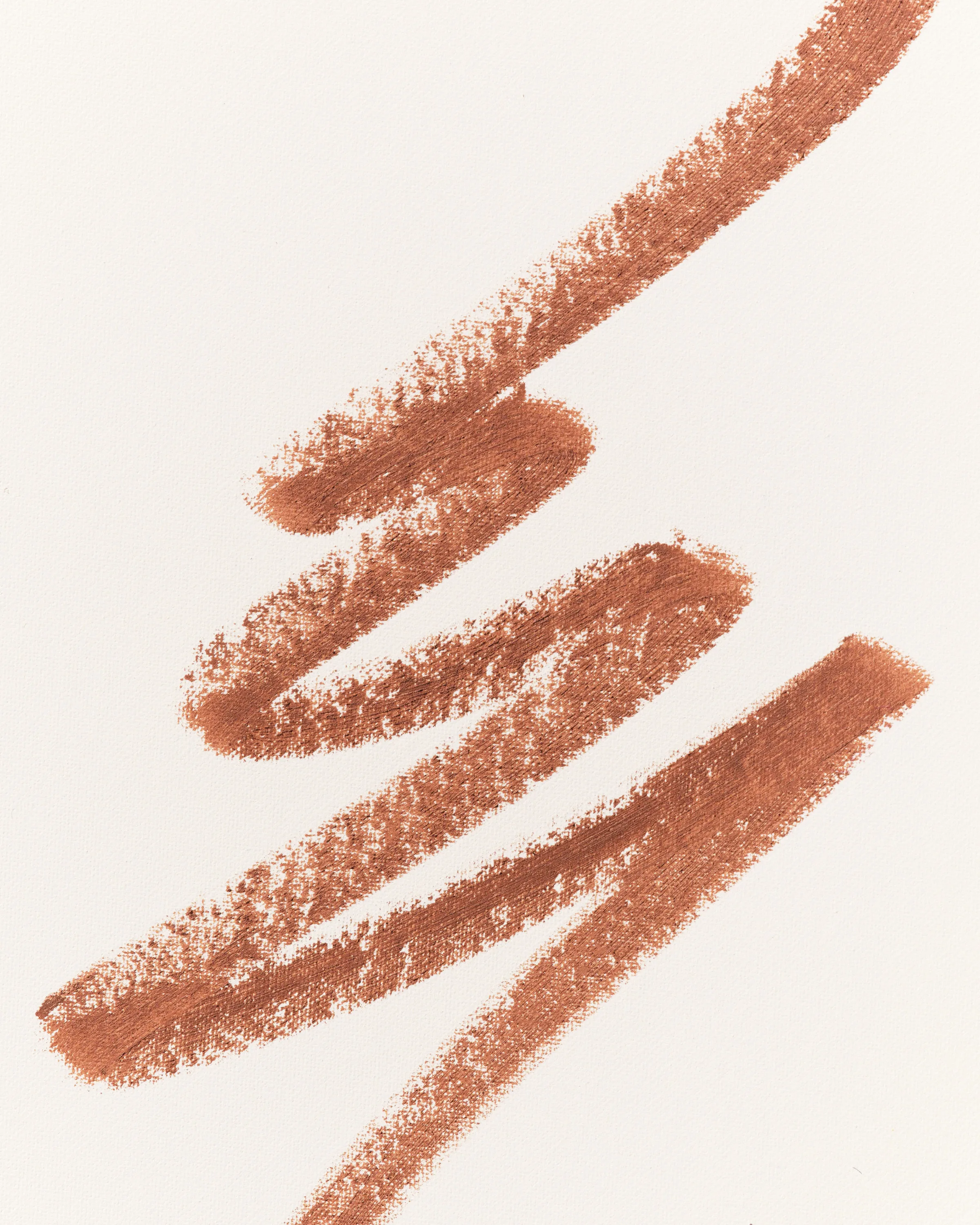 Zigzag swatch of a warm brown Iced Latte lip liner on textured white paper, for Kylie Cosmetics.