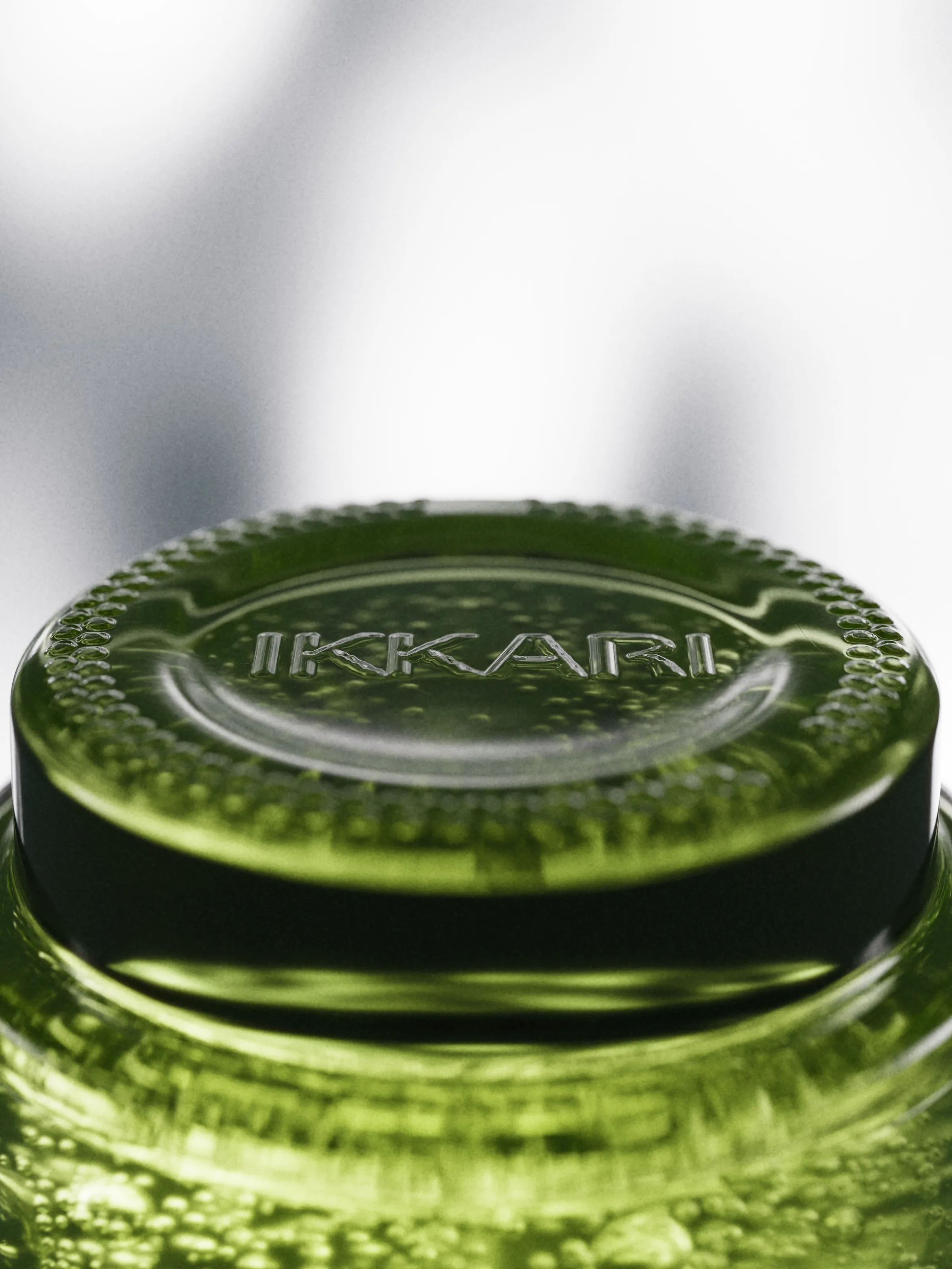 CGI render of a green glass bottle top embossed with IKKARI, filled with bubbles against a soft grey backdrop, for Ikkari.