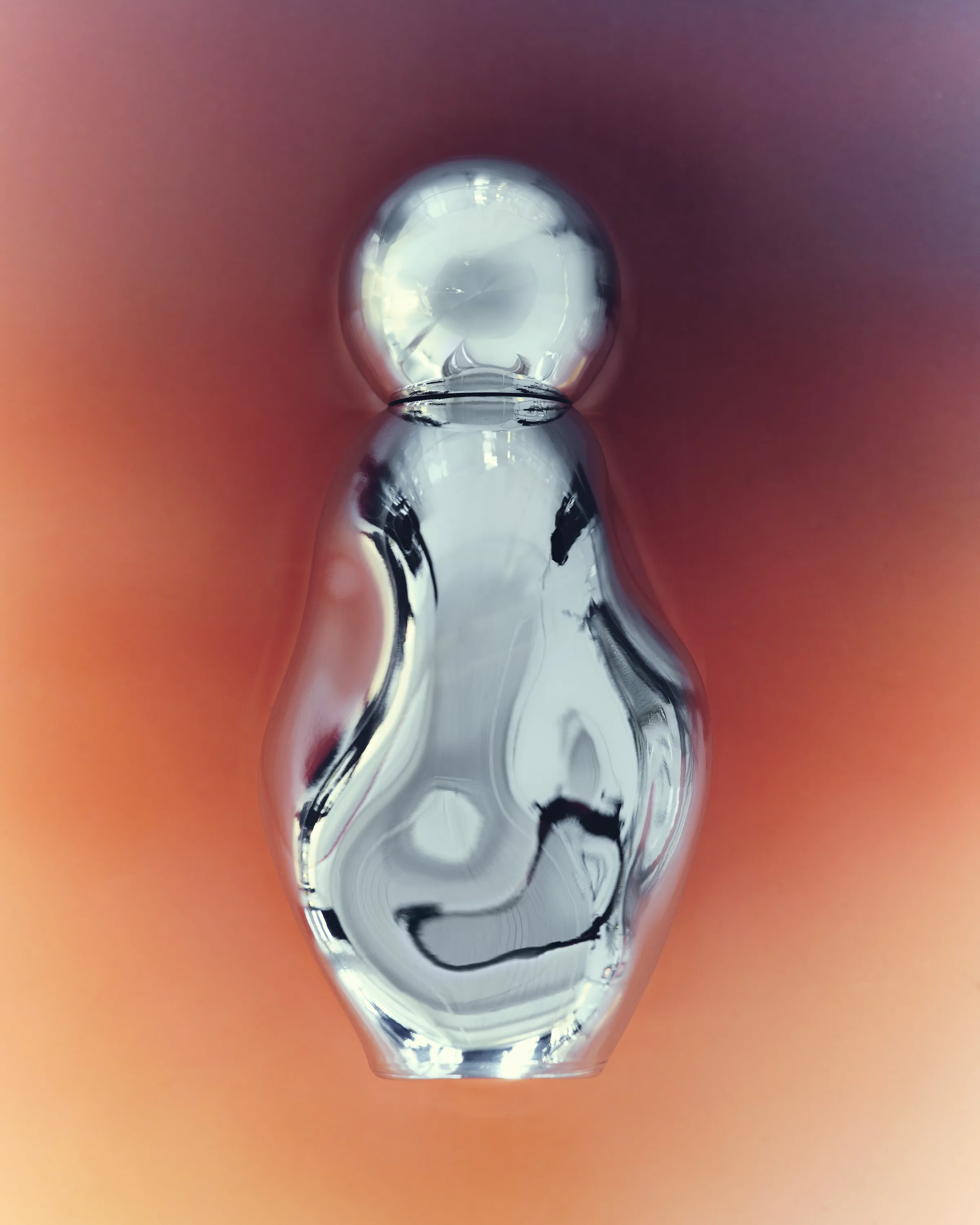 Organic chrome perfume bottle with round cap against a glowing orange and purple gradient, for Kylie Cosmetics.
