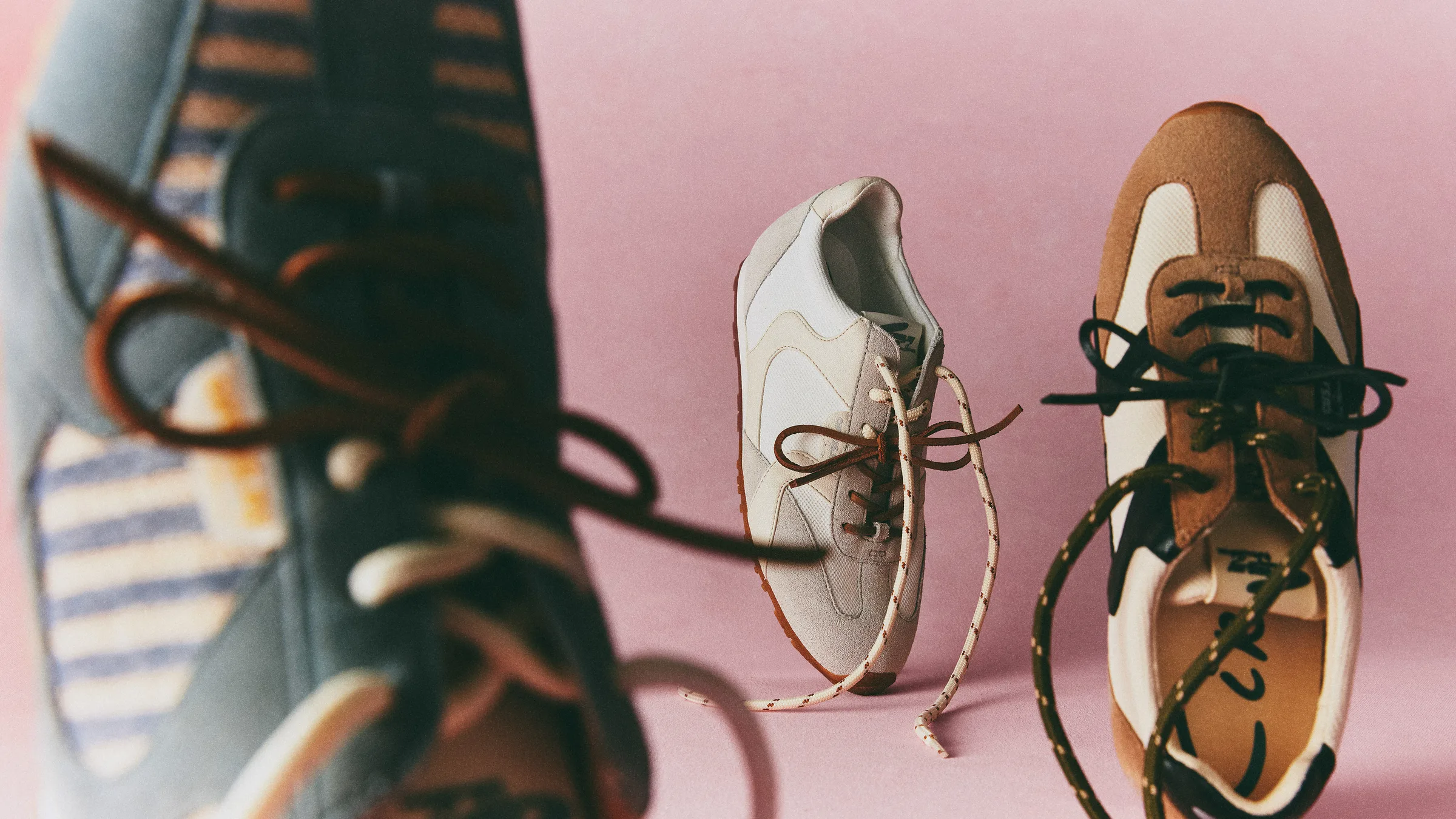 Retro suede Nash sneakers with contrast laces standing on a pink backdrop, one blurred in the foreground, for Circus NY.