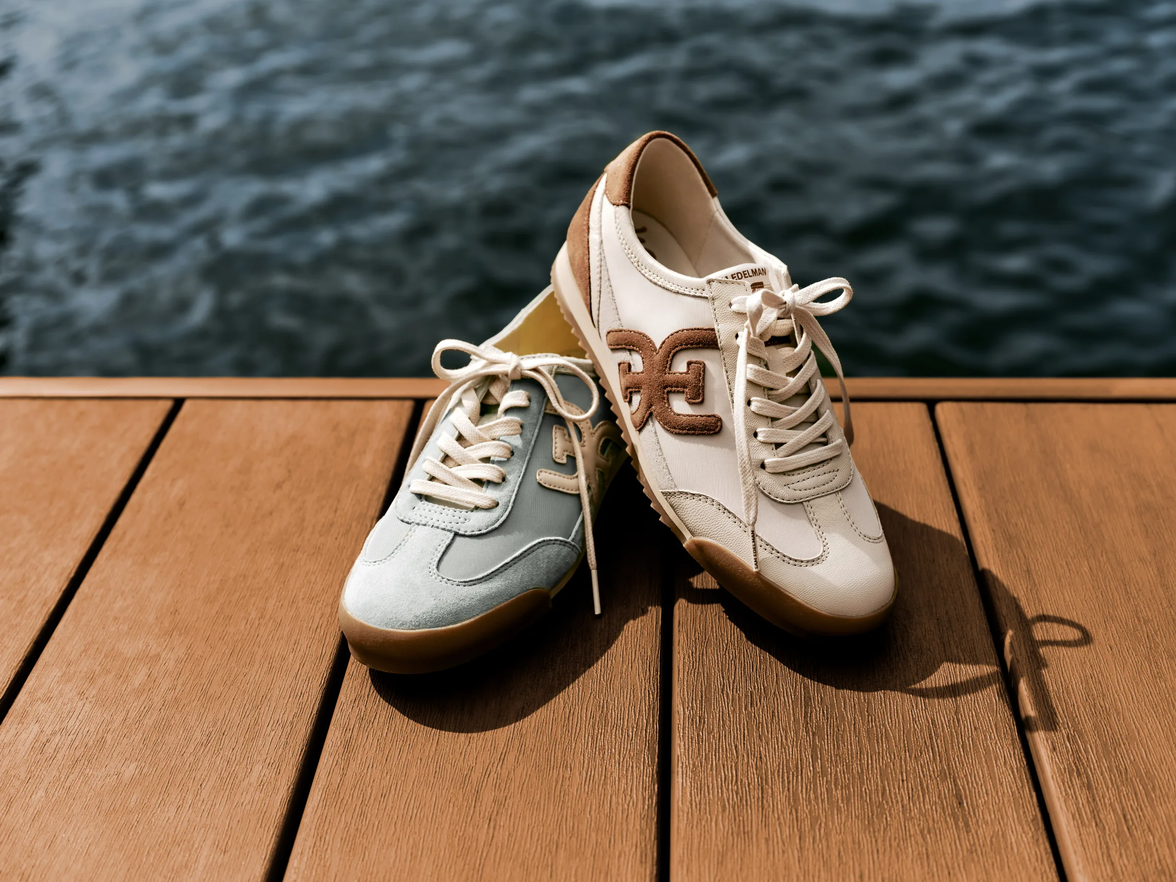 Cream and sage suede retro sneakers with brown logo on a wooden dock above dark water, for Sam Edelman.