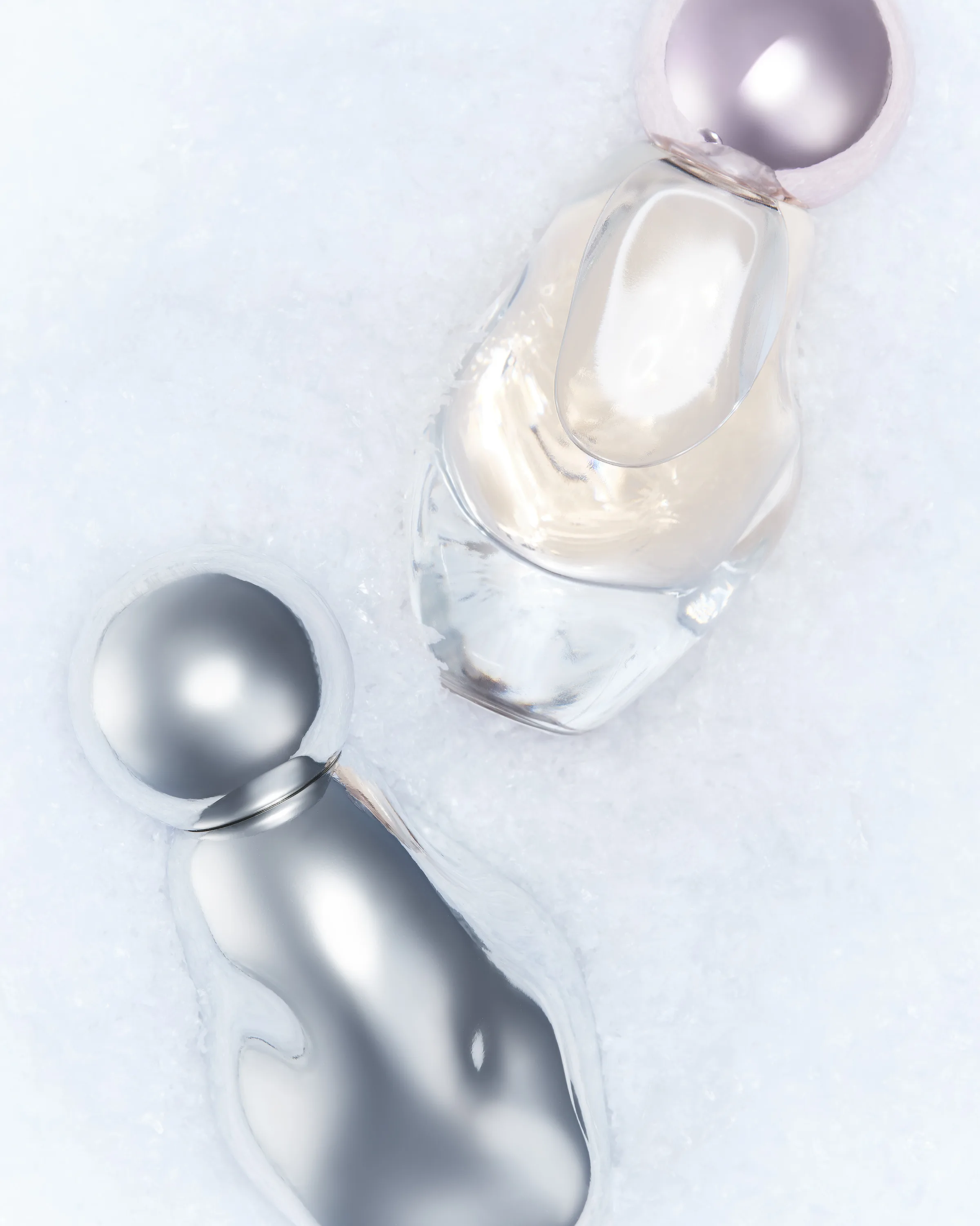 Chrome and clear Cosmic perfume bottles nestled in white snow, shot from above, for Kylie Cosmetics.