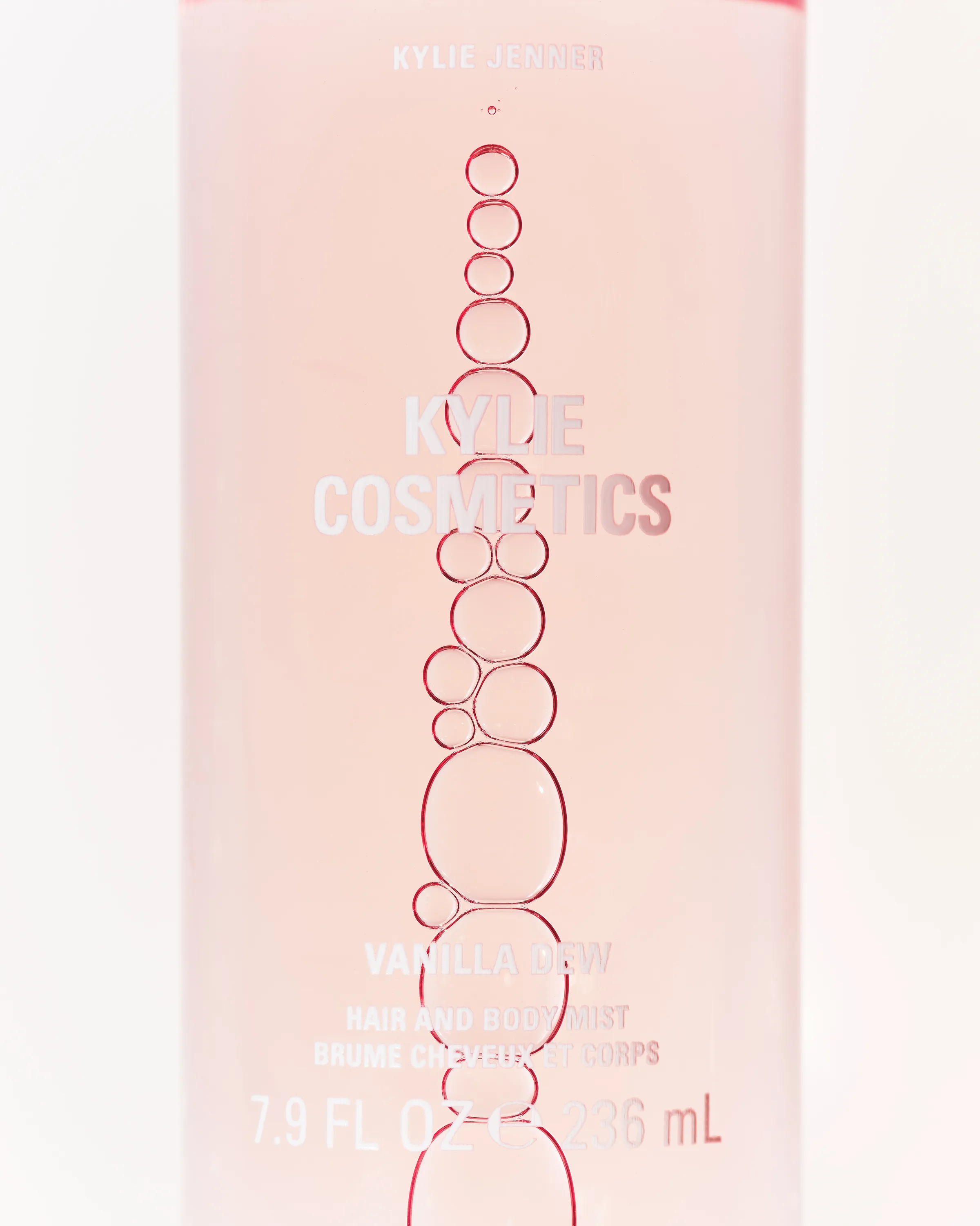 Close-up of pink Vanilla Dew hair and body mist bottle with a column of red-rimmed bubbles, for Kylie Cosmetics.