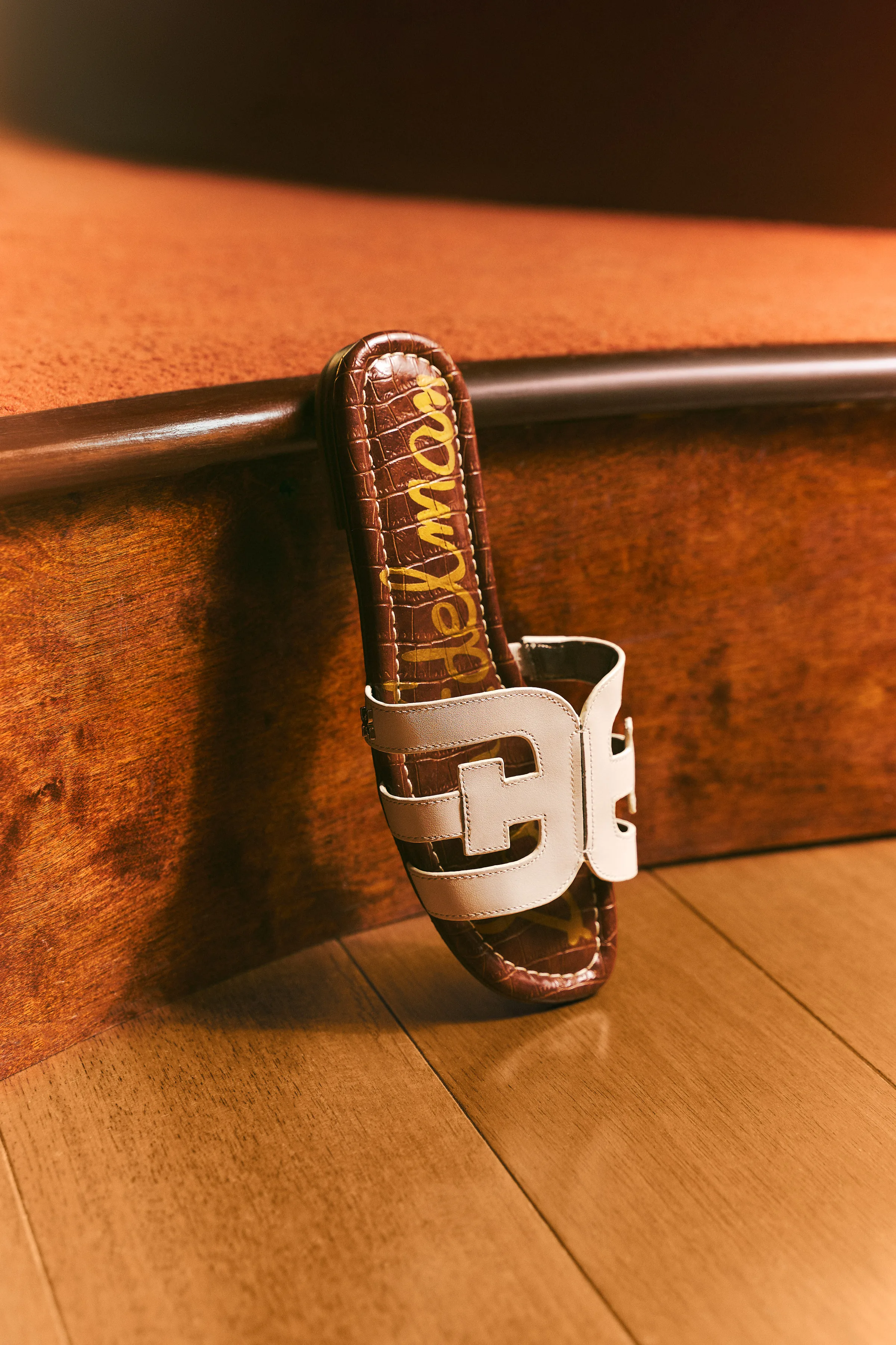 Cream leather slide sandal with double-E strap and croc-embossed footbed propped on a wood ledge, for Sam Edelman.