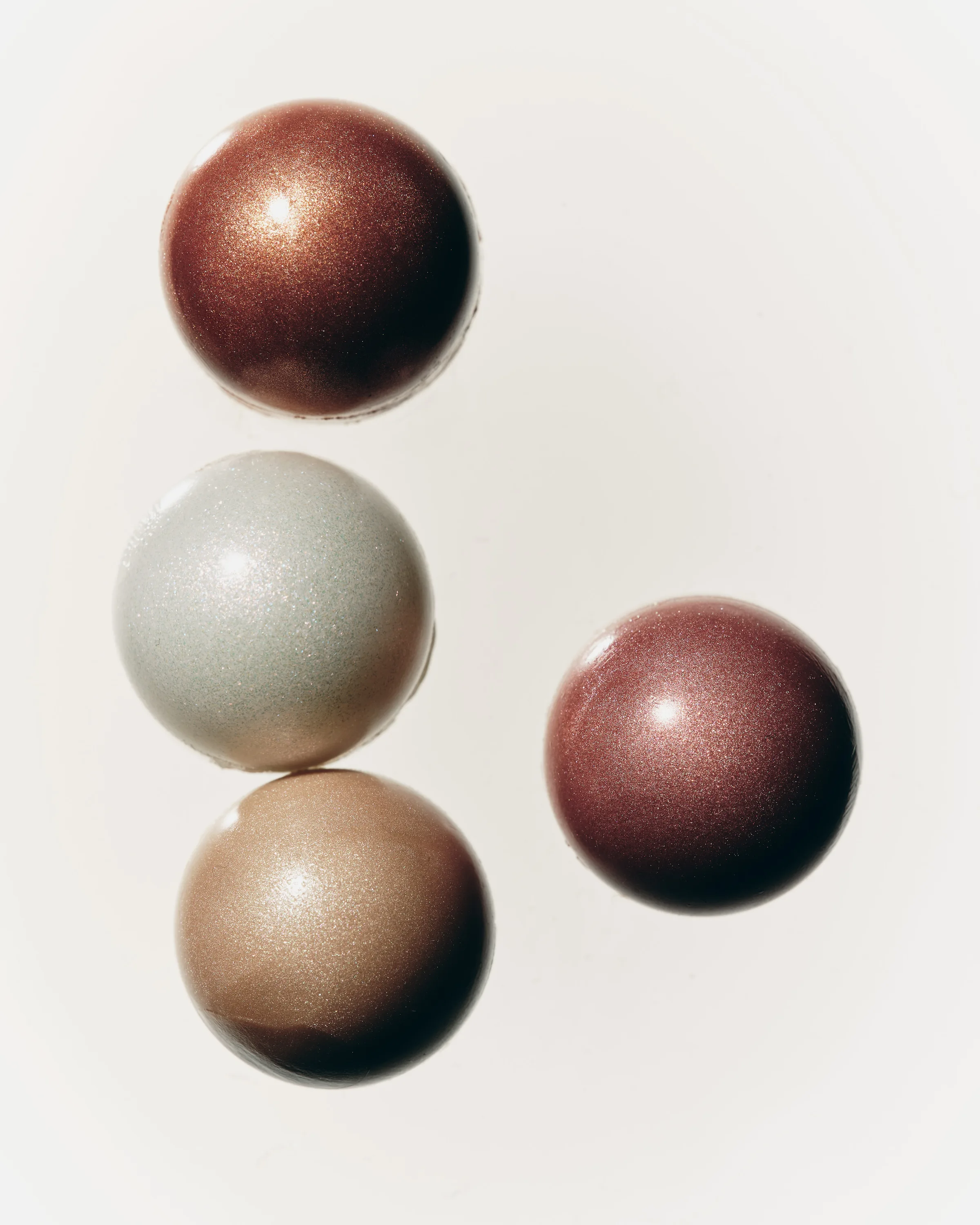 Four shimmering balm spheres in bronze, pearl, gold and rose on a white background, for Kylie Cosmetics.