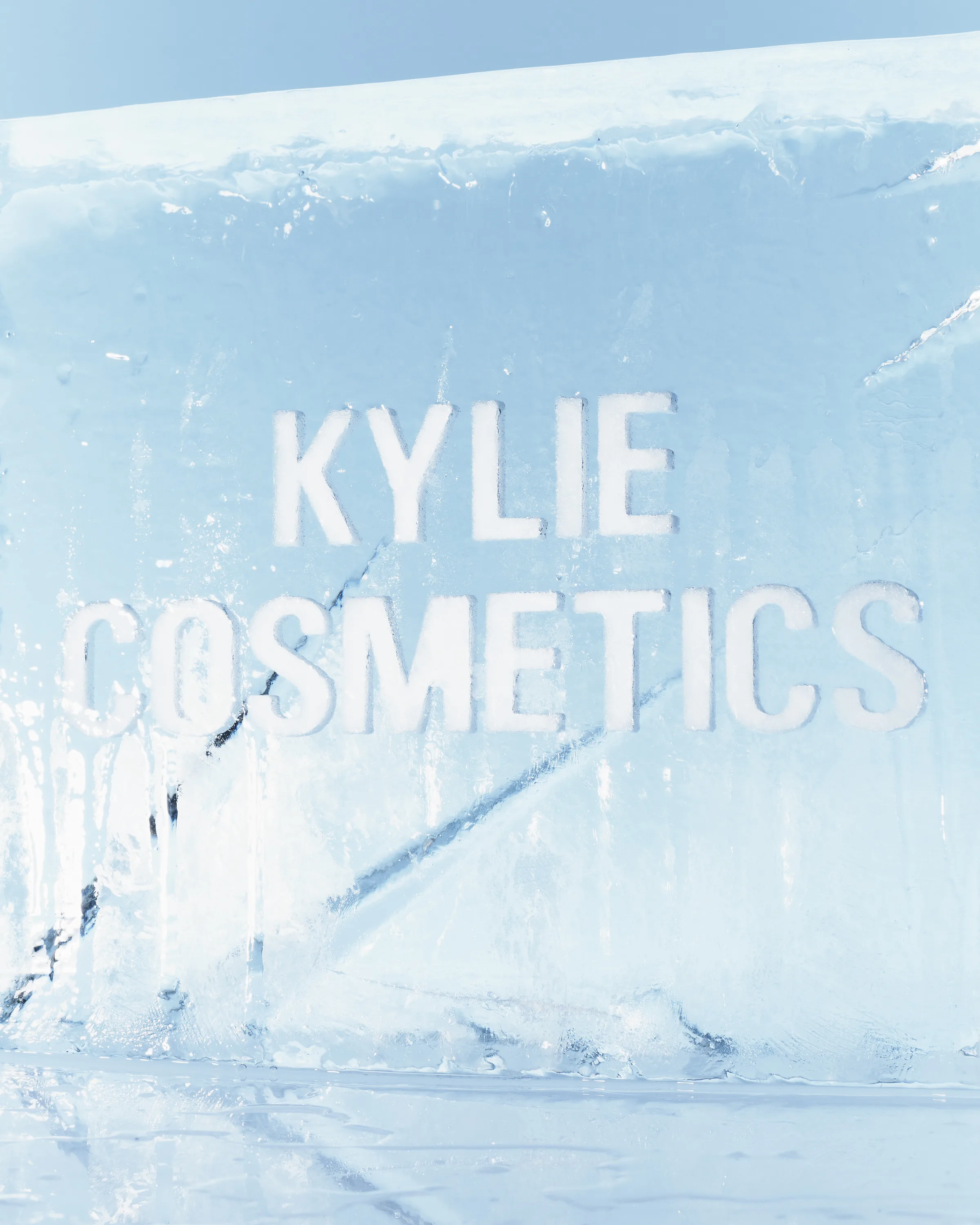 Kylie Cosmetics name carved into a clear ice block against a pale blue background for a holiday campaign, for Kylie Cosmetics.