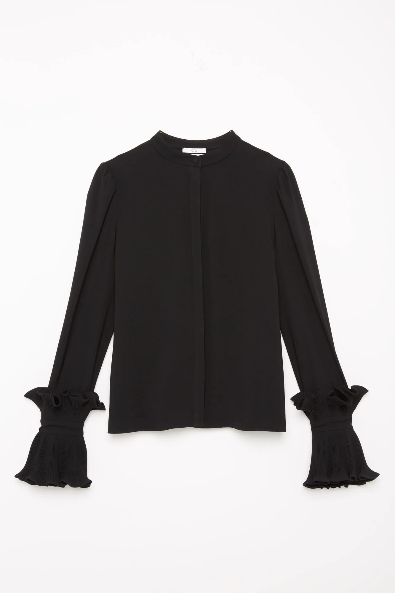 Black band-collar blouse with ruffled pleated cuffs laid flat on a white background, for Co Collections.