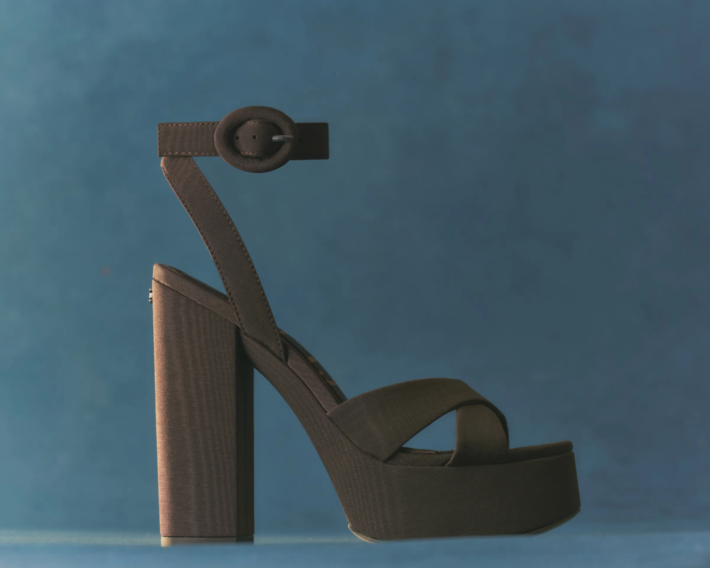 Cocoa fabric platform sandal with crossed straps and buckled ankle strap on a blue backdrop, for Sam Edelman.