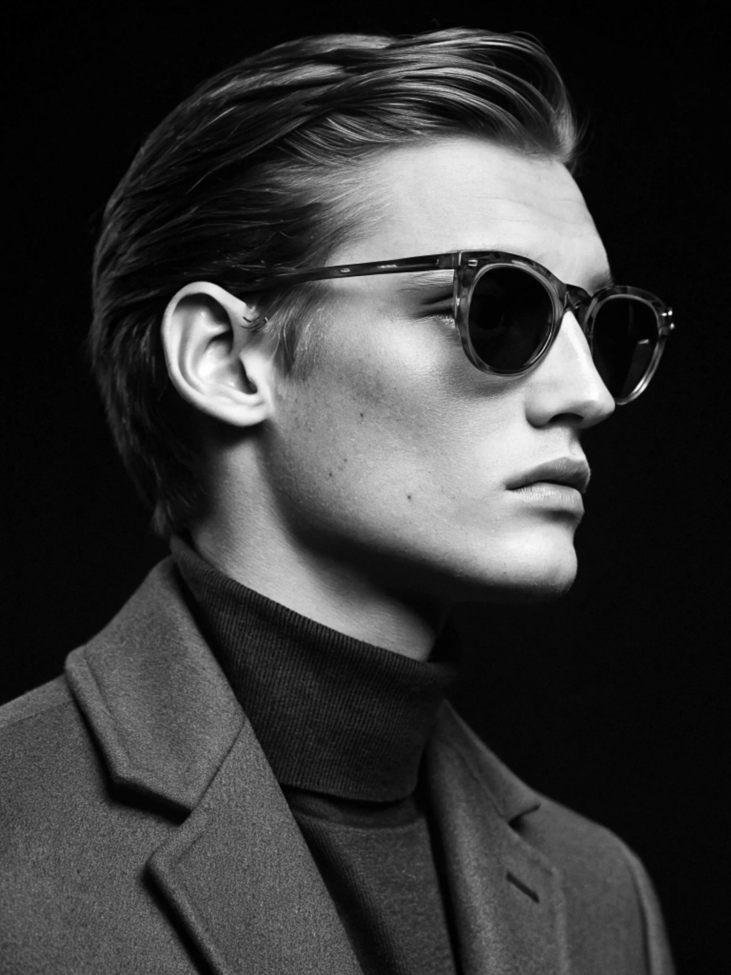 AI image of a man in profile wearing translucent sunglasses, turtleneck and wool coat in black and white. Persol AI Concept.