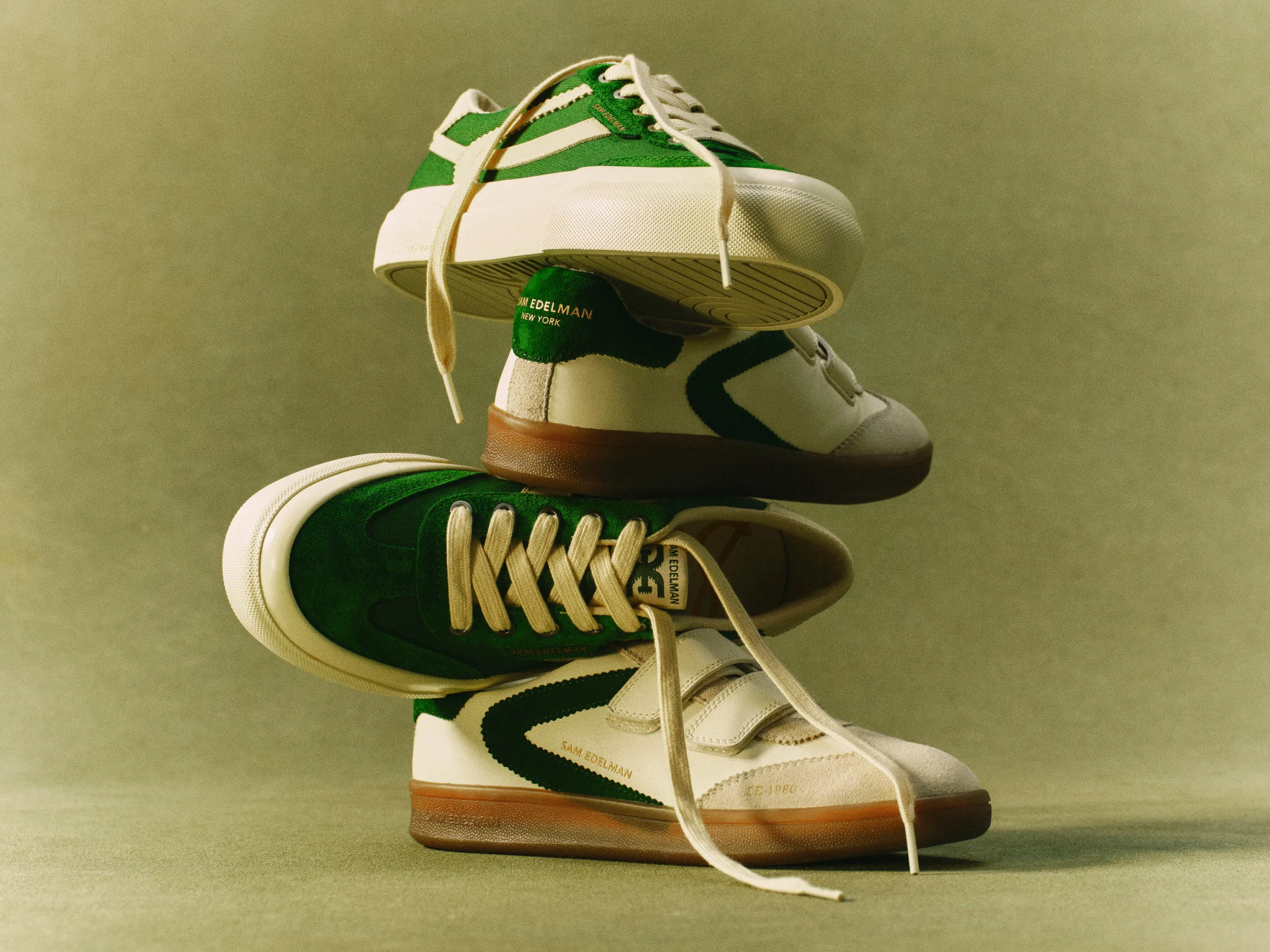 Stack of green and cream suede retro sneakers with gum soles on an olive backdrop, for Sam Edelman.