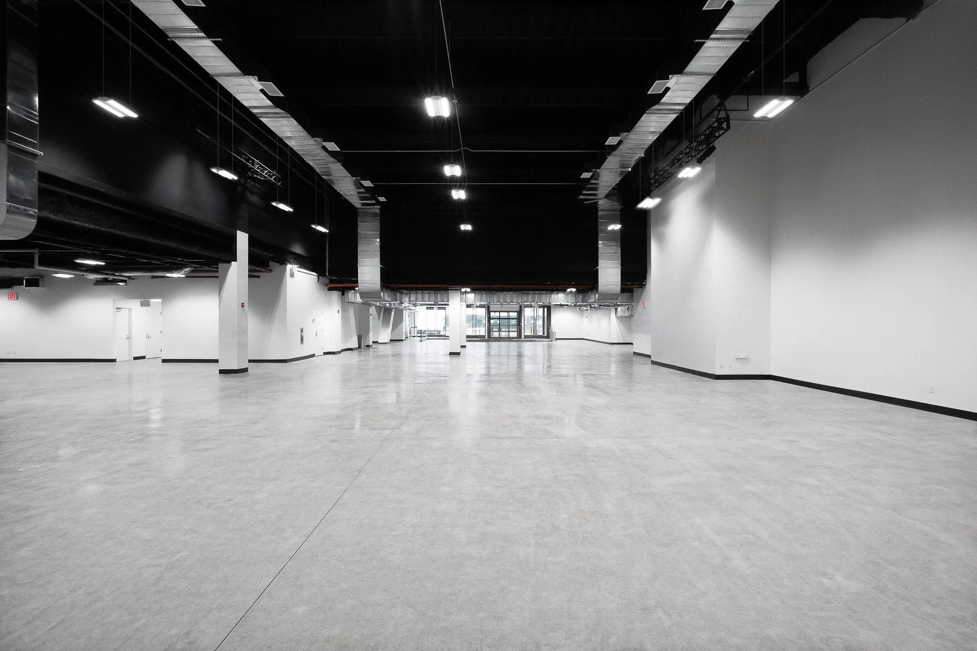 Empty Studio 2 at Slate Studios with white walls, grey concrete floor, columns and black ceiling with hanging lights.