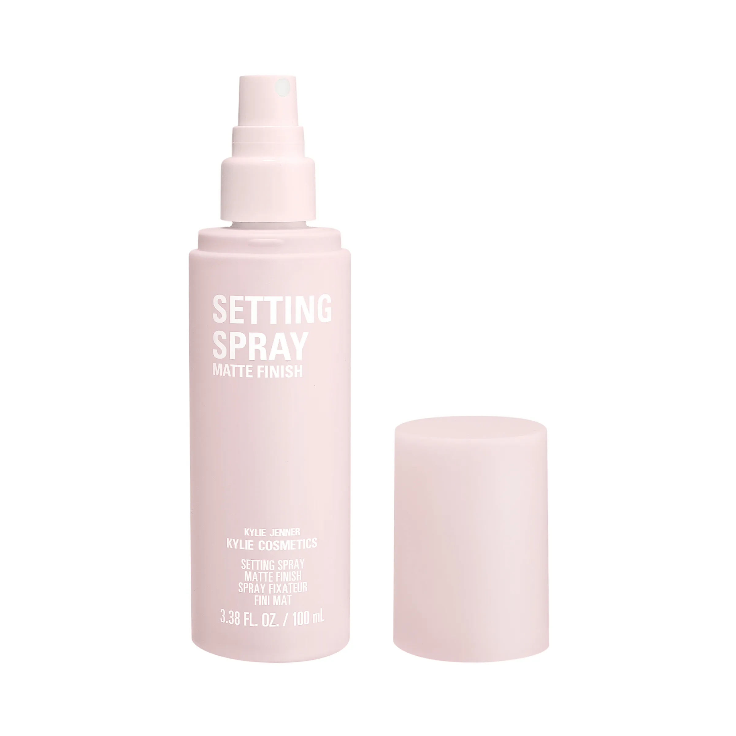 Pale pink matte finish setting spray bottle with its cap removed beside it on a white background, for Kylie Cosmetics.