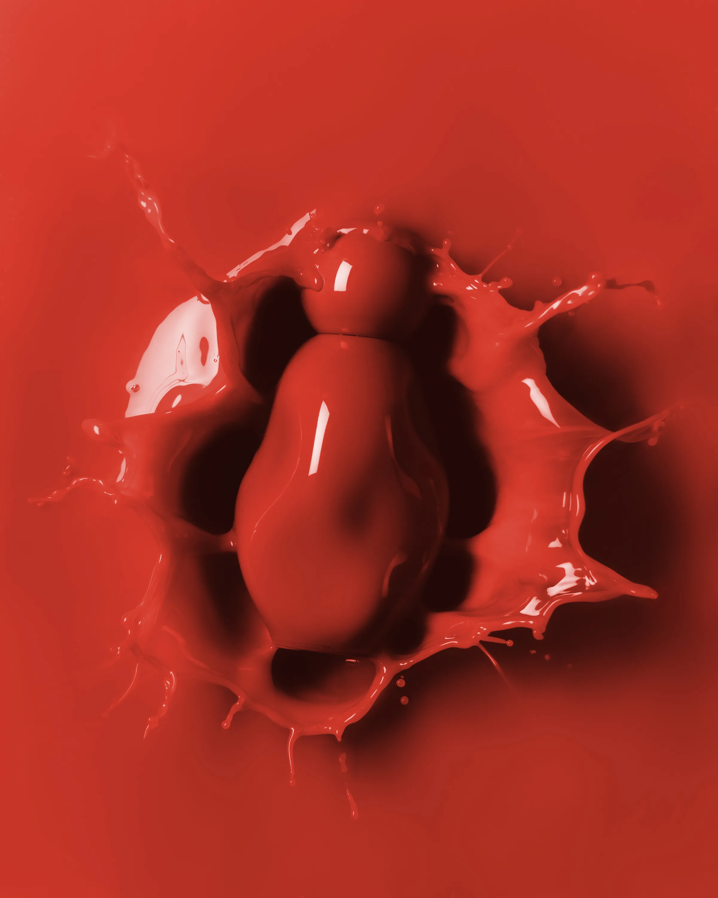 Red glossy fragrance bottle sinking into a splash of red liquid on a red background, for Kylie Cosmetics.