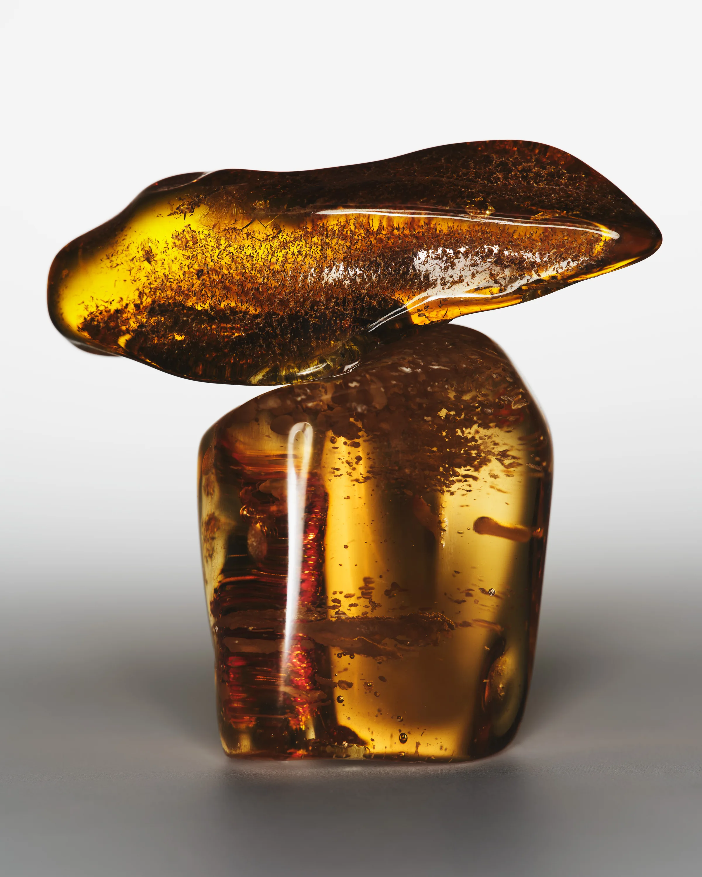 Two polished amber stones balanced on each other, glowing golden against a grey gradient backdrop, for Kylie Cosmetics.