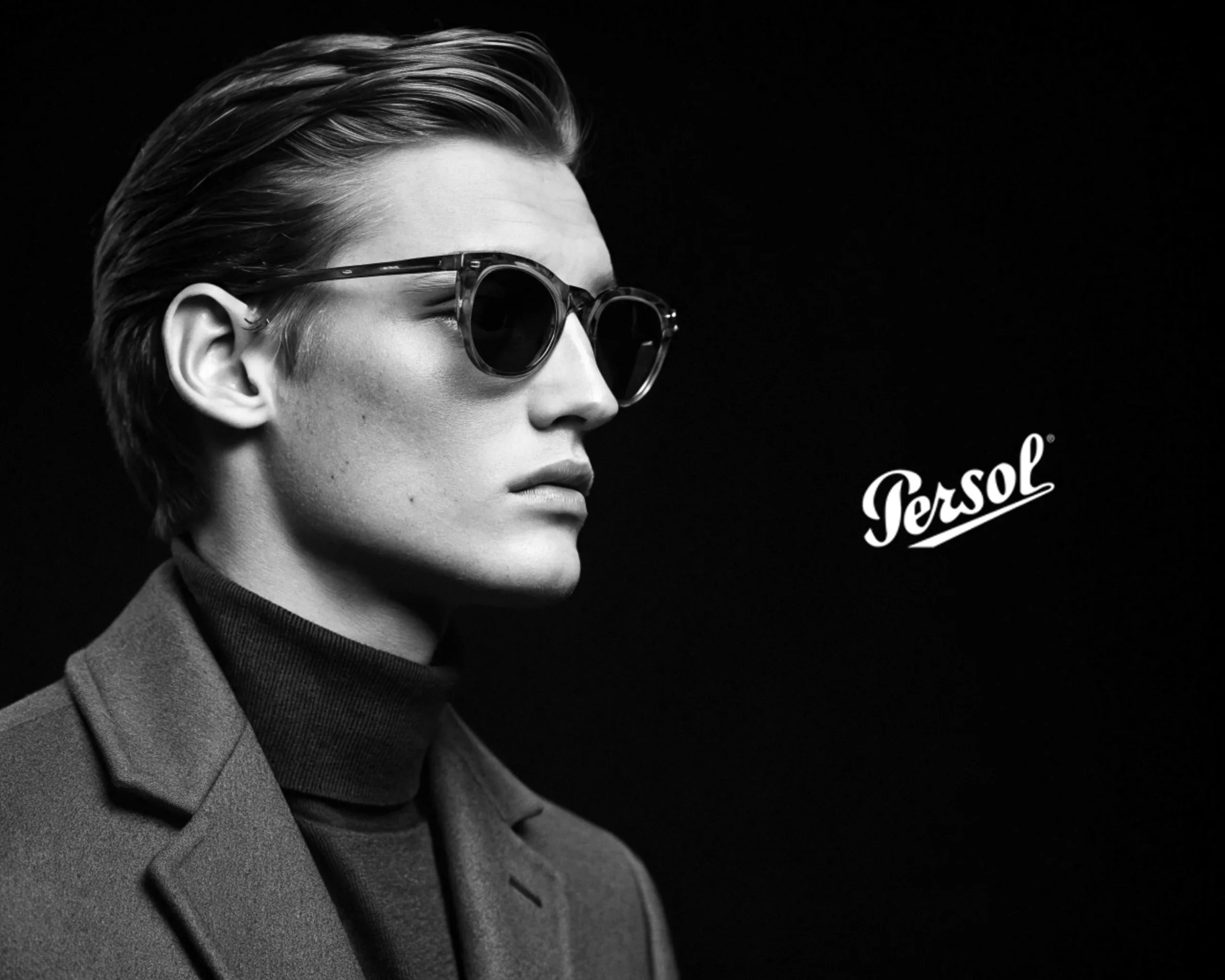 AI image of a man in profile wearing tortoiseshell sunglasses, turtleneck and wool coat, in black and white. Persol AI Concept.