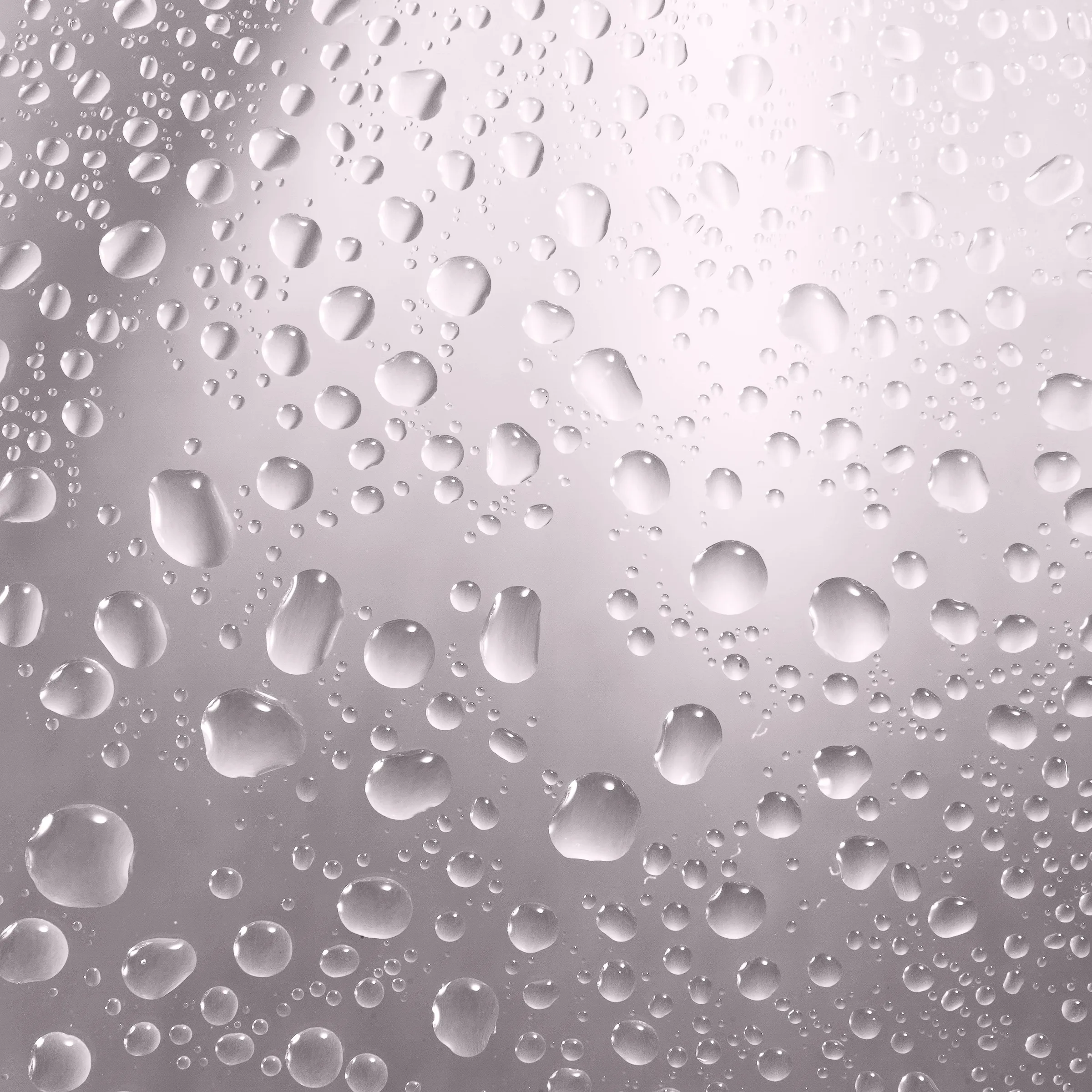 Close-up of water droplets beaded on a soft pink-grey glass surface, for Kylie Cosmetics.