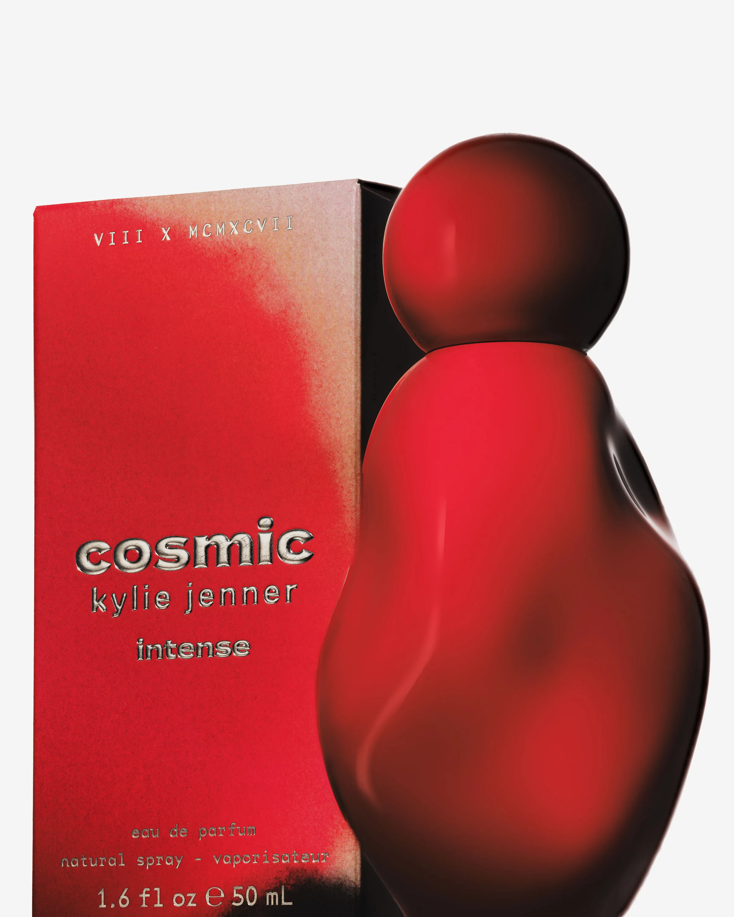 Red sculpted Cosmic Intense eau de parfum bottle beside its red box on a light grey background, for Kylie Jenner.