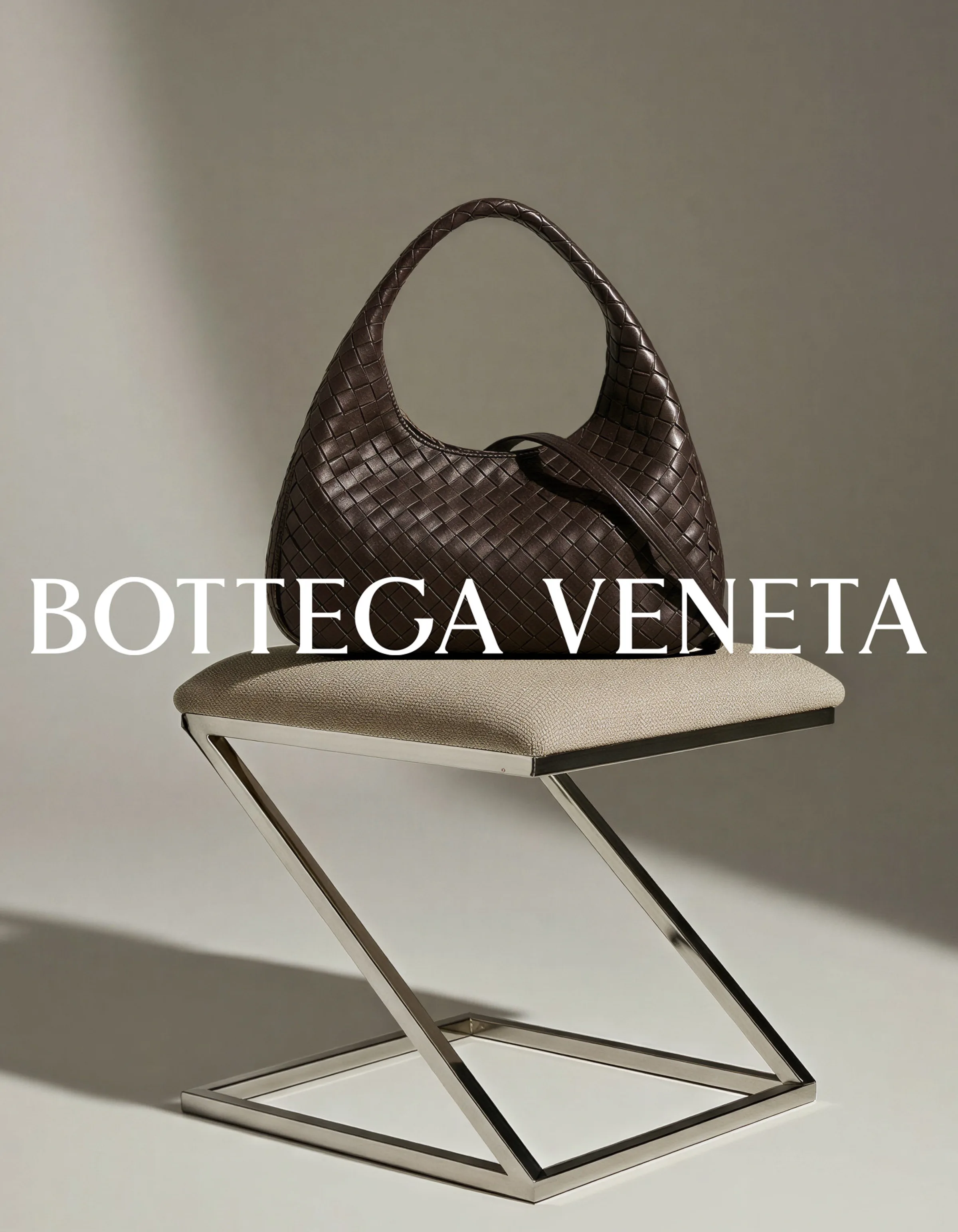 AI image of a brown woven leather hobo bag on a linen stool with a chrome Z-frame, under the brand wordmark. Bottega Veneta AI Concept.