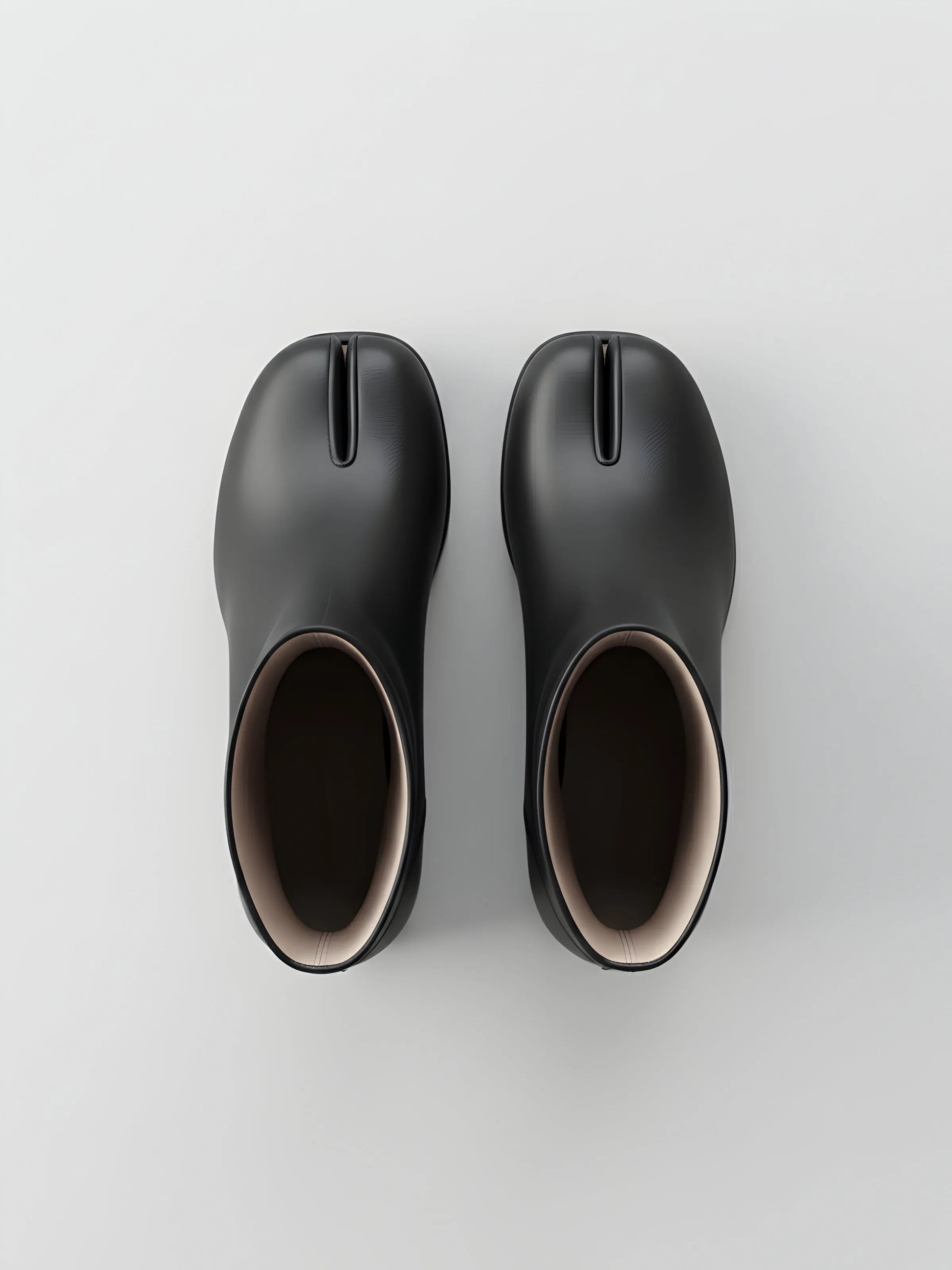 AI image of black leather split-toe Tabi ankle boots seen from above on a pale grey background. Maison Margiela AI Concept.