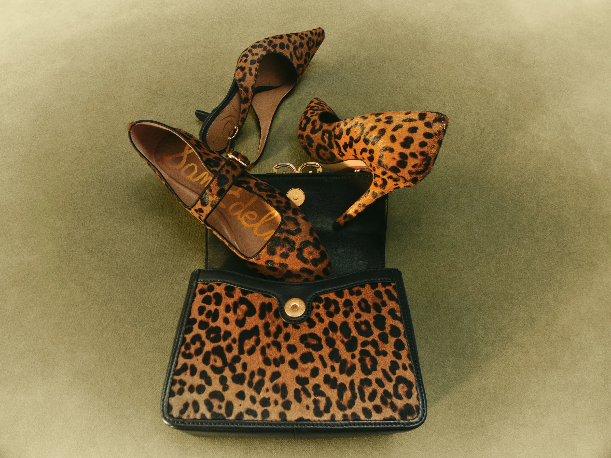 Leopard-print calf hair pumps, slingback and flat spilling from a matching open crossbody bag on olive velvet, for Sam Edelman.