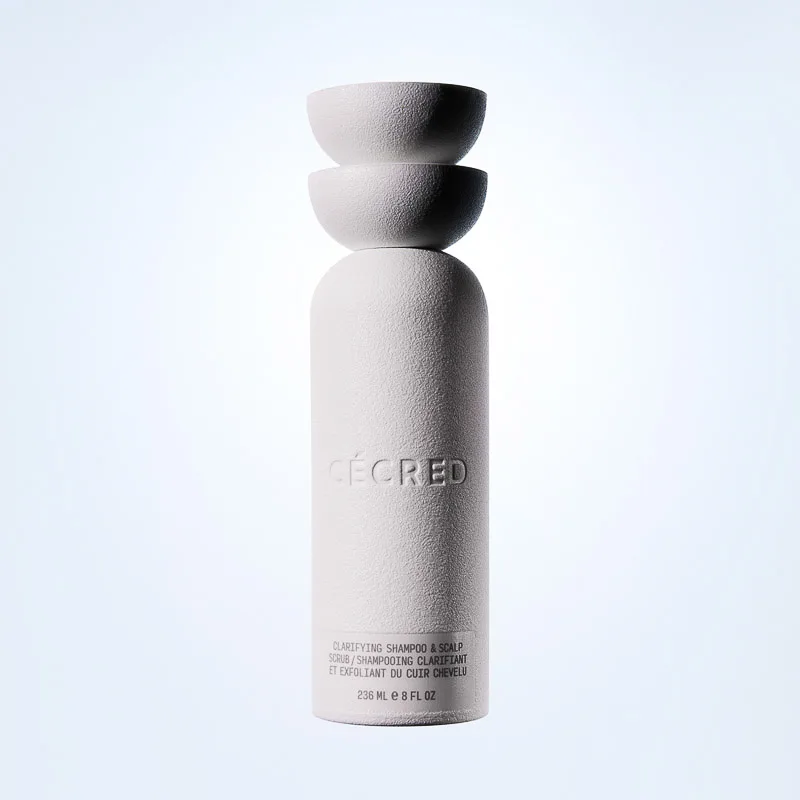 Textured white Clarifying Shampoo & Scalp Scrub bottle with stacked bowl cap on a pale blue backdrop, for Cécred.