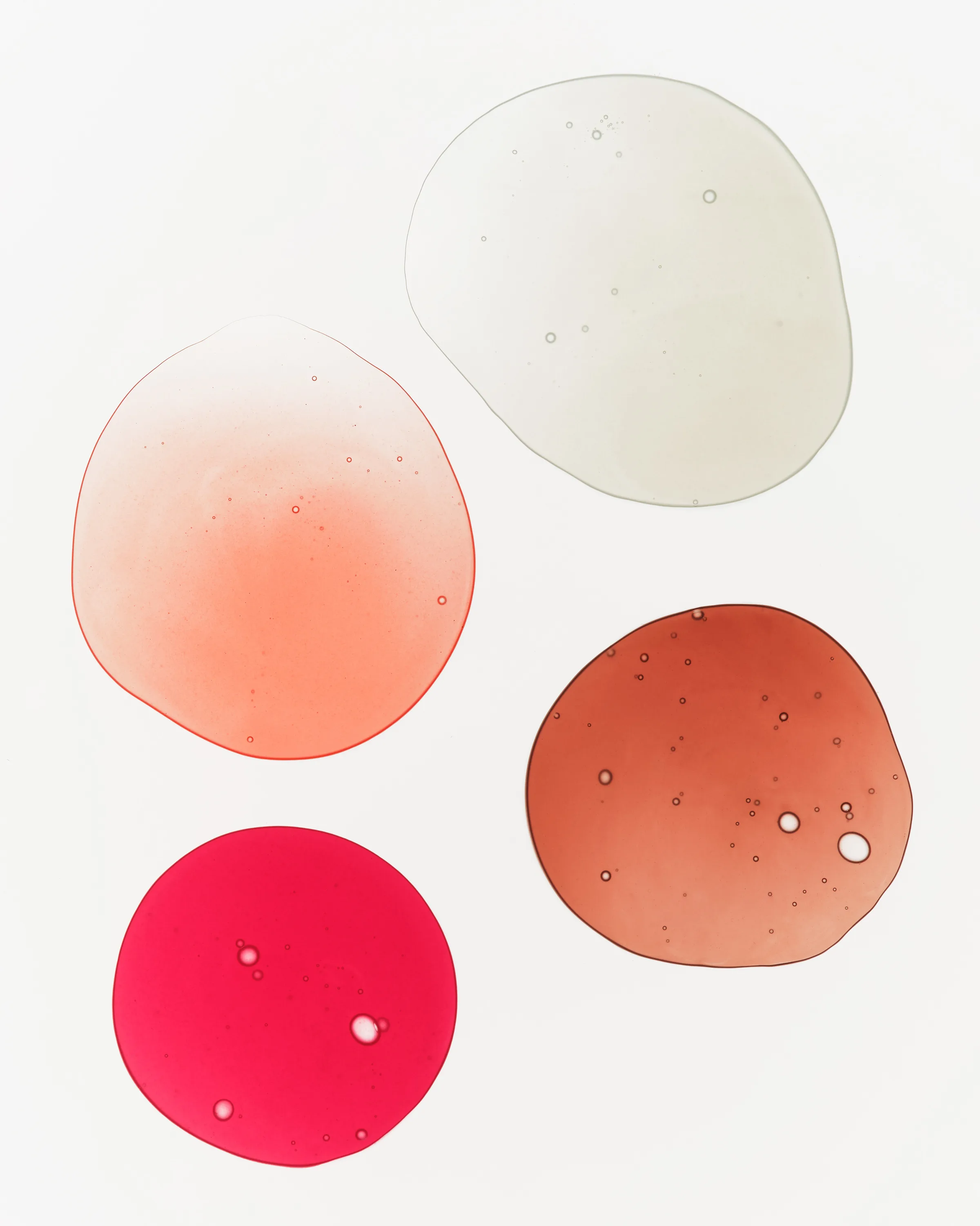Four translucent lip oil swatches in clear, peach, pink and terracotta on a white background, for Kylie Cosmetics.