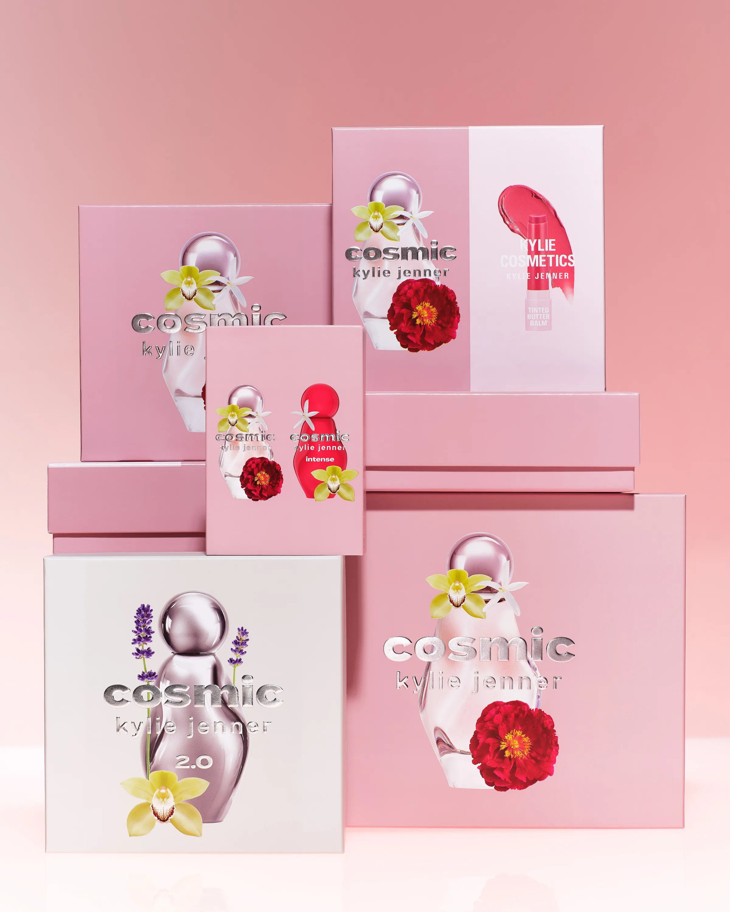 Stacked pink Cosmic Kylie Jenner fragrance gift boxes with flower artwork on a pink gradient backdrop, for Kylie Cosmetics.