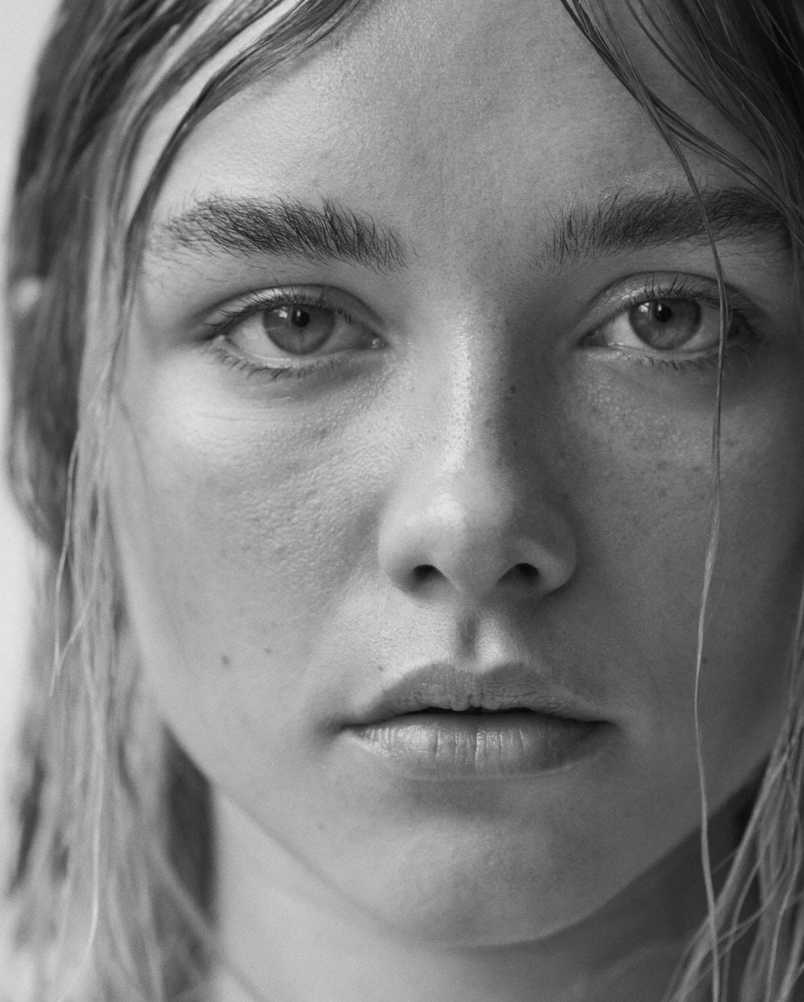 Black and white close-up portrait of a woman with wet hair and freckled skin, for The Last Magazine.