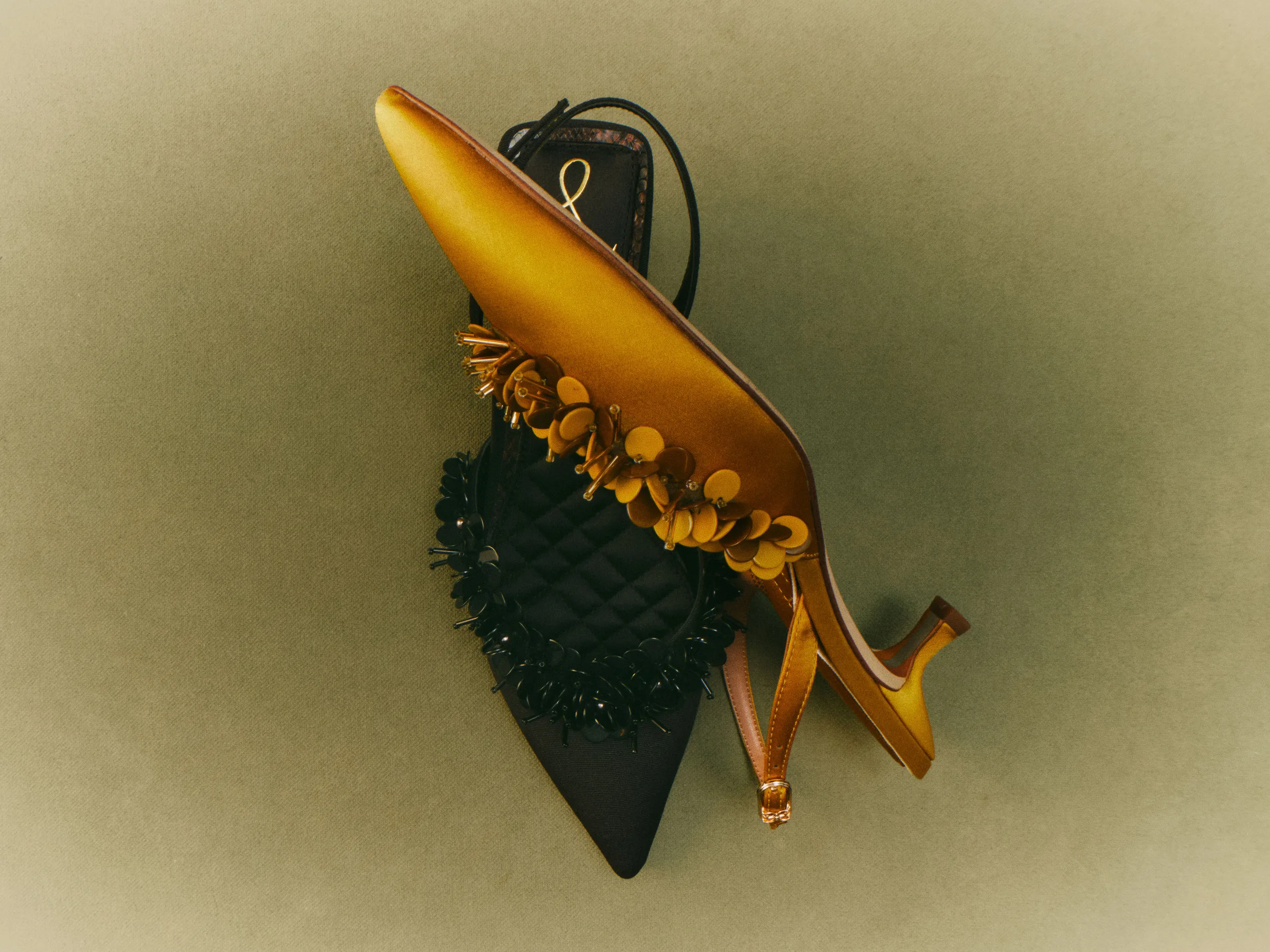 Mustard satin and black slingback heels with sequin flower trim, crossed on an olive backdrop, for Sam Edelman.
