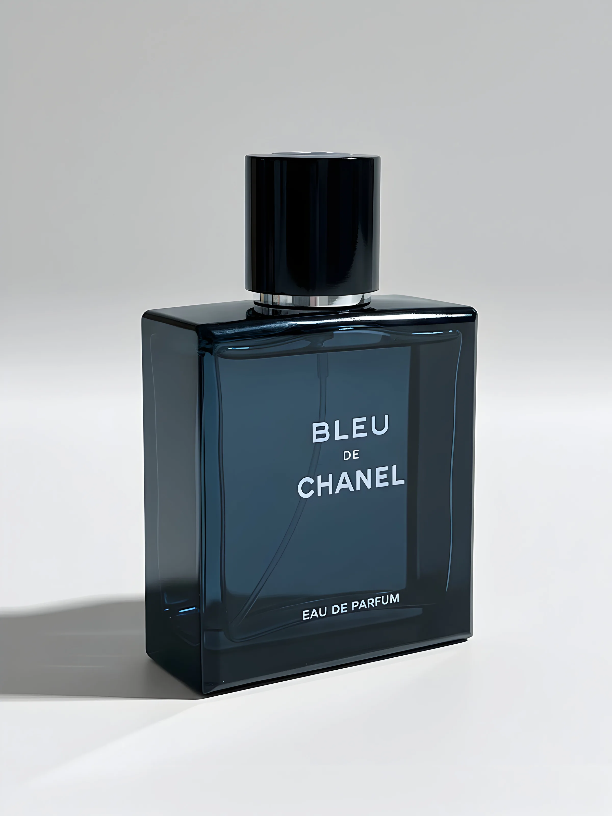 AI image of a dark blue Bleu de Chanel eau de parfum bottle with black cap on a pale grey background. Chanel AI Concept.