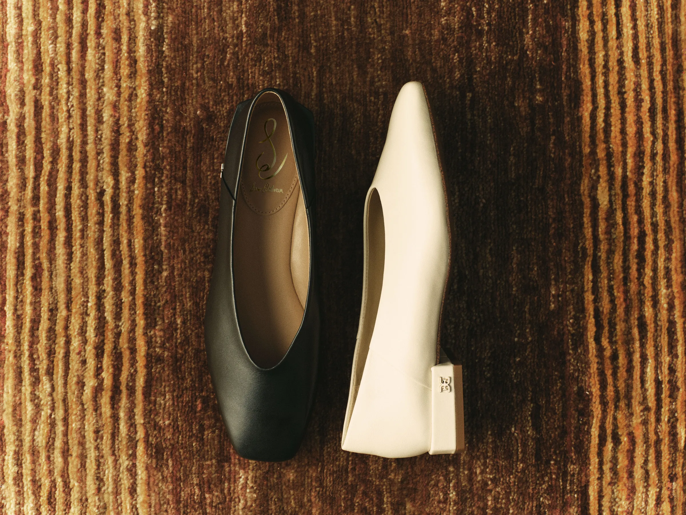 Black and ivory leather square-toe flats laid side by side on a striped brown rug, for Sam Edelman.