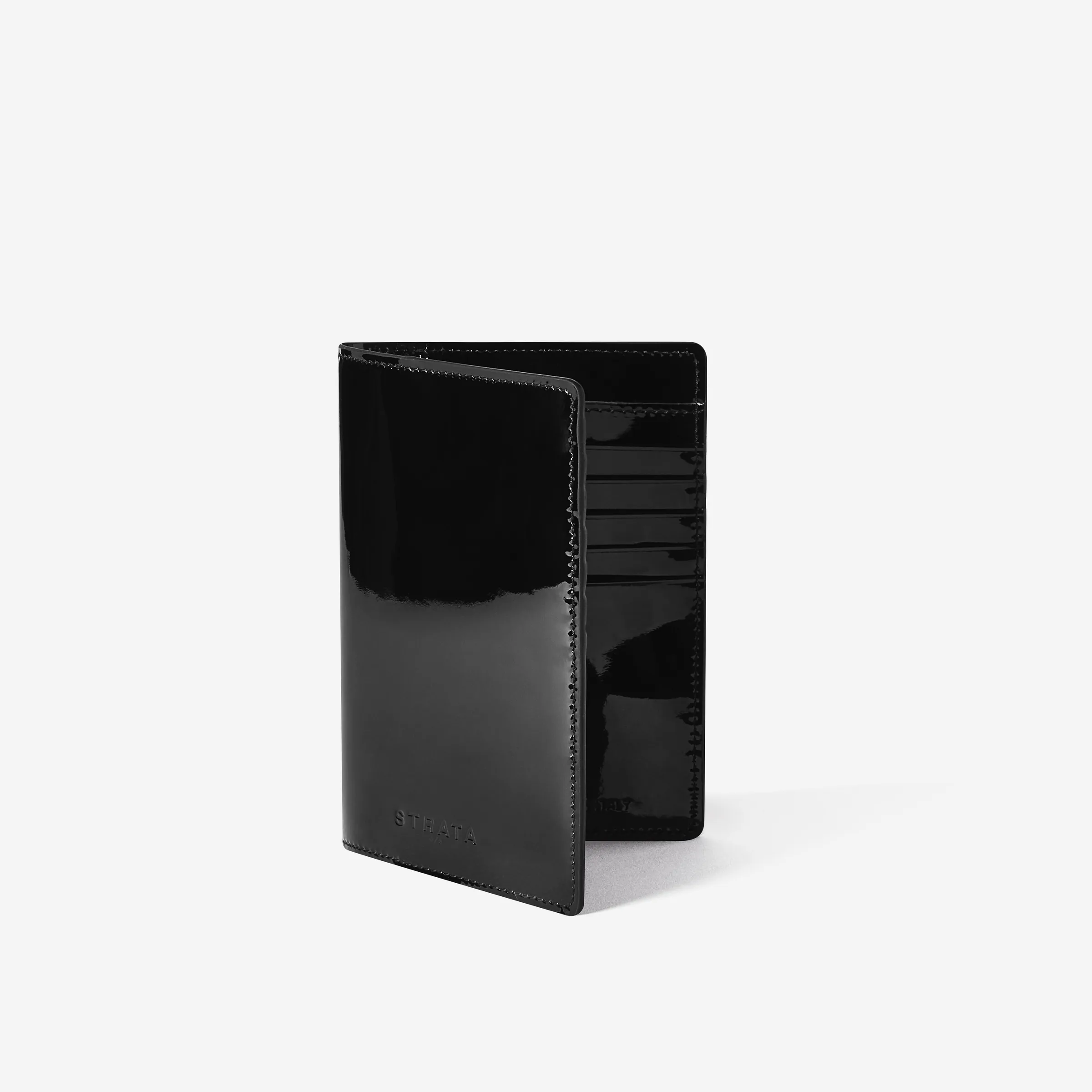 Black patent leather travel sleeve standing half open with card slots, three-quarter view on white, for Strata.