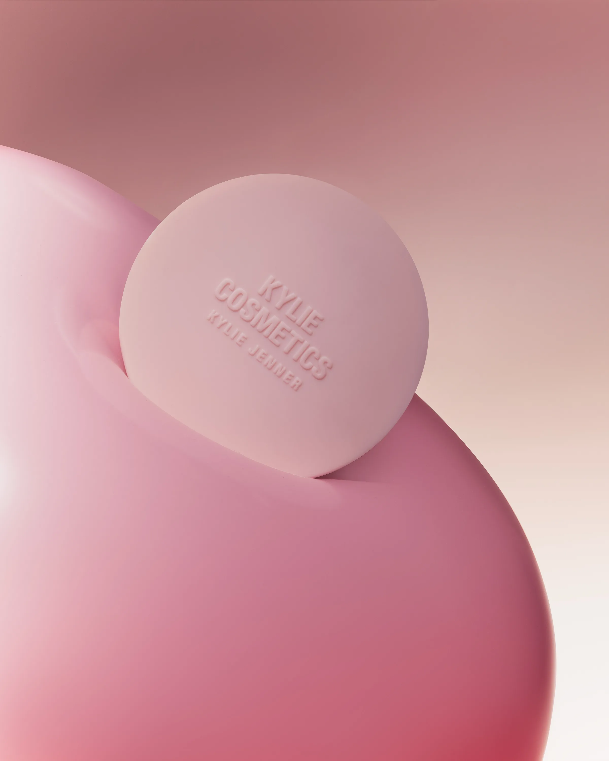 CGI render of a pink embossed blush compact nestled in a glossy pink balloon shape on a muted pink background, for Kylie Cosmetics.