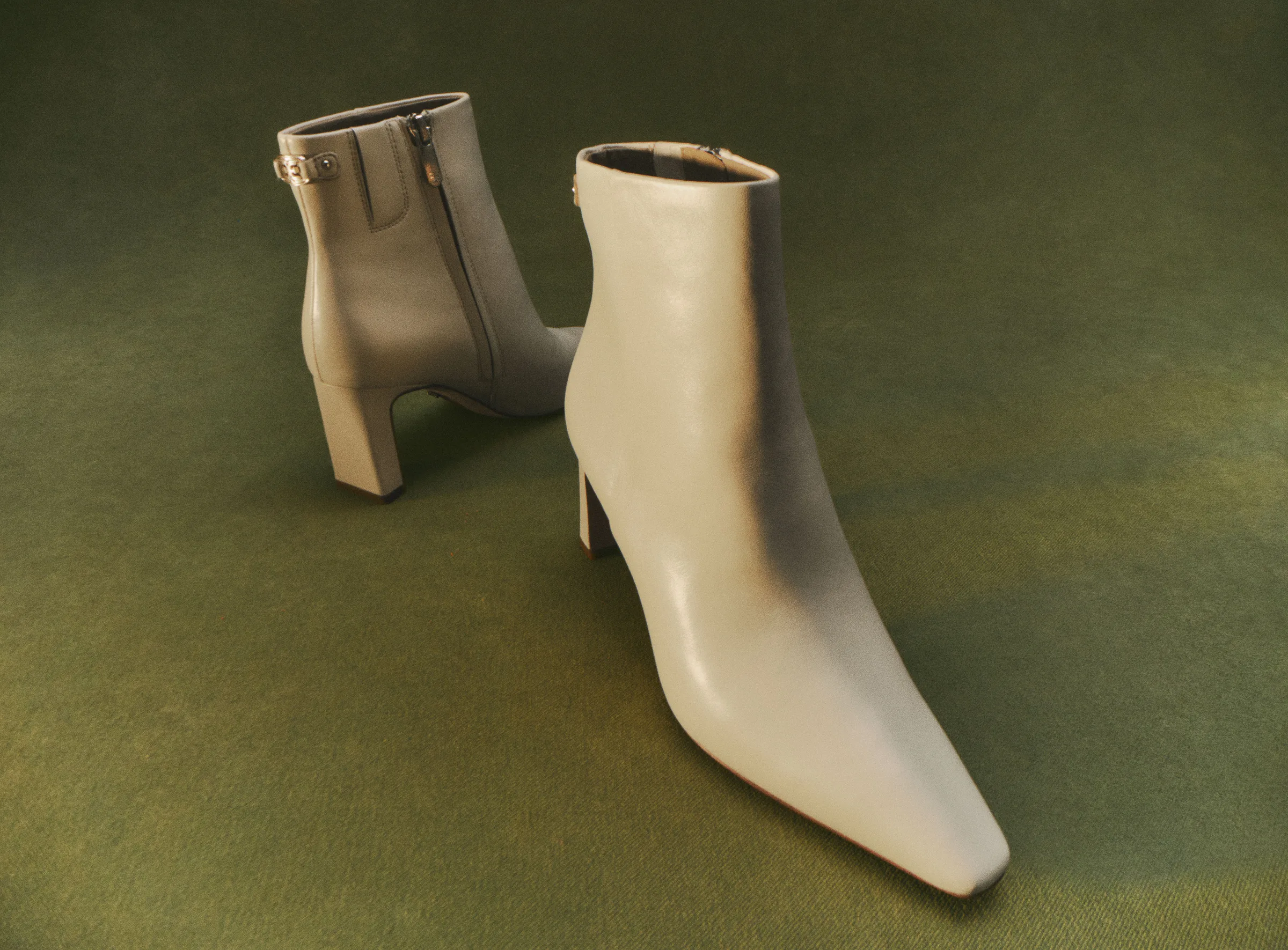 Pair of ivory leather pointed-toe ankle boots with block heels on a green felt surface, for Sam Edelman.