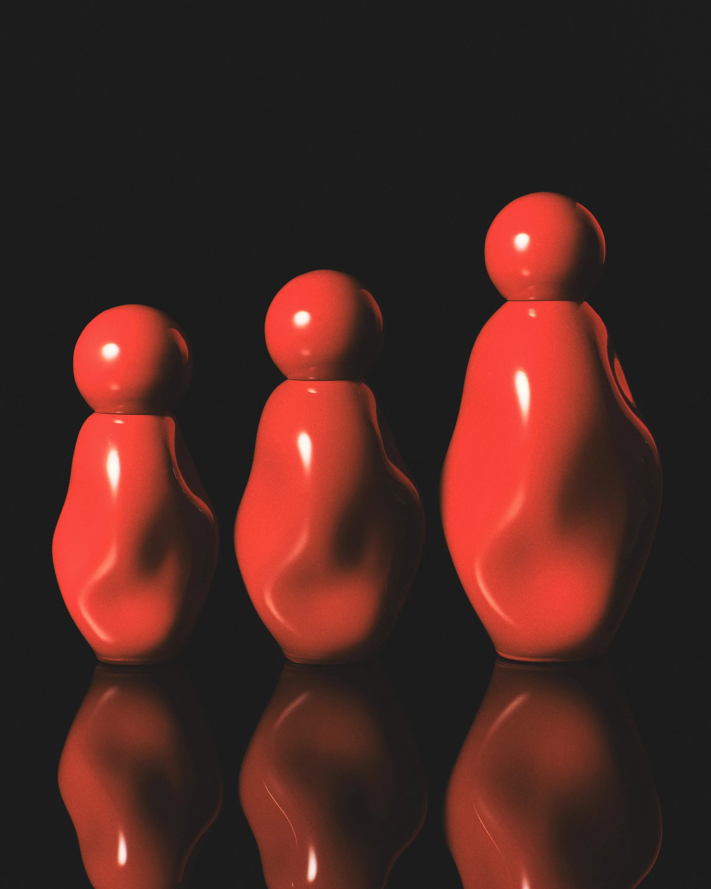 CGI render of three glossy red sculpted fragrance bottles in ascending sizes on a reflective black surface, for Kylie Cosmetics.
